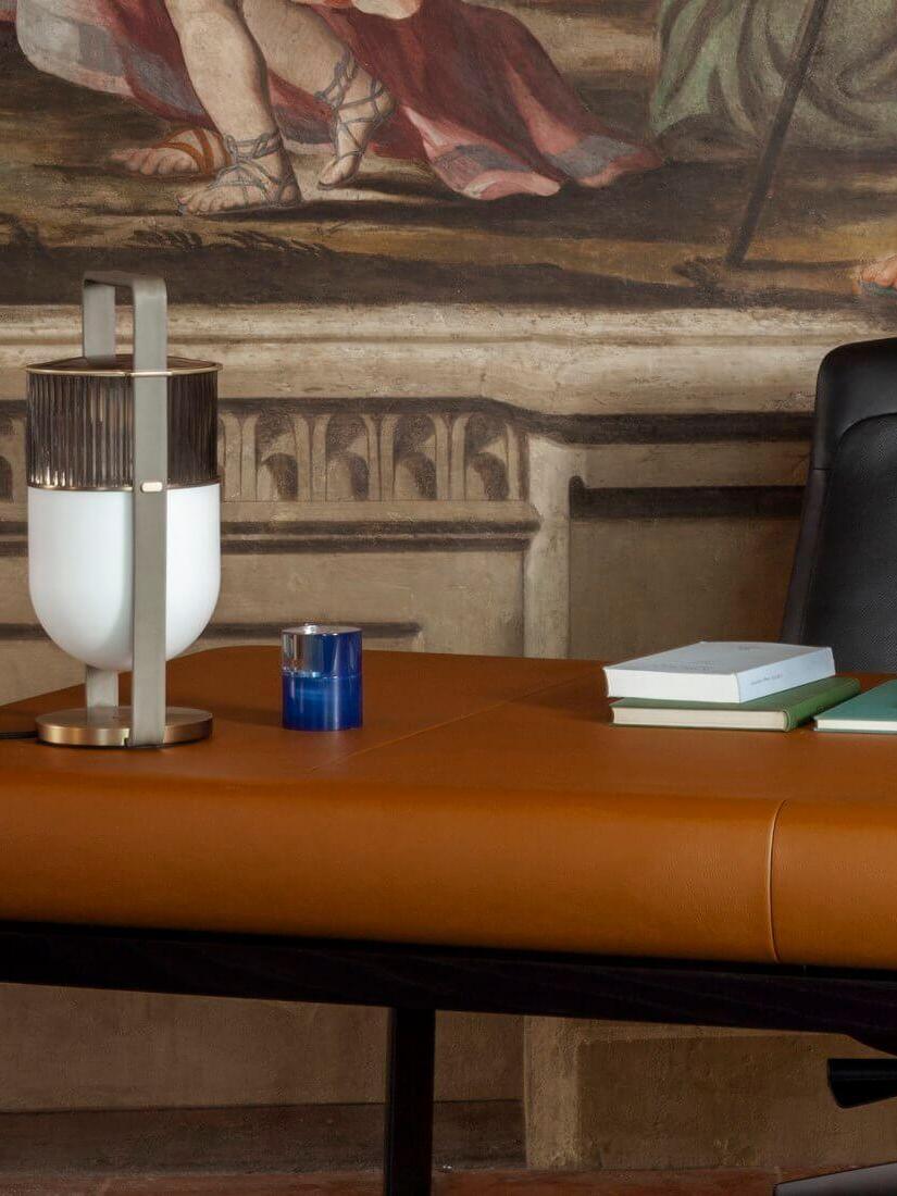 Cropped view of two Xi lamps on an orange cabinet beside a blue glass, books and framed artwork