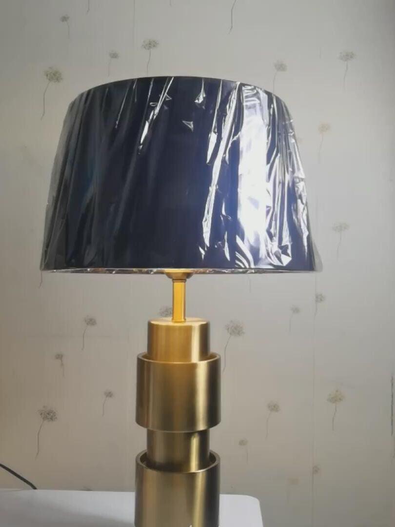 Jean lamp with protective wrapping over the black shade and its gold-tone base visible below