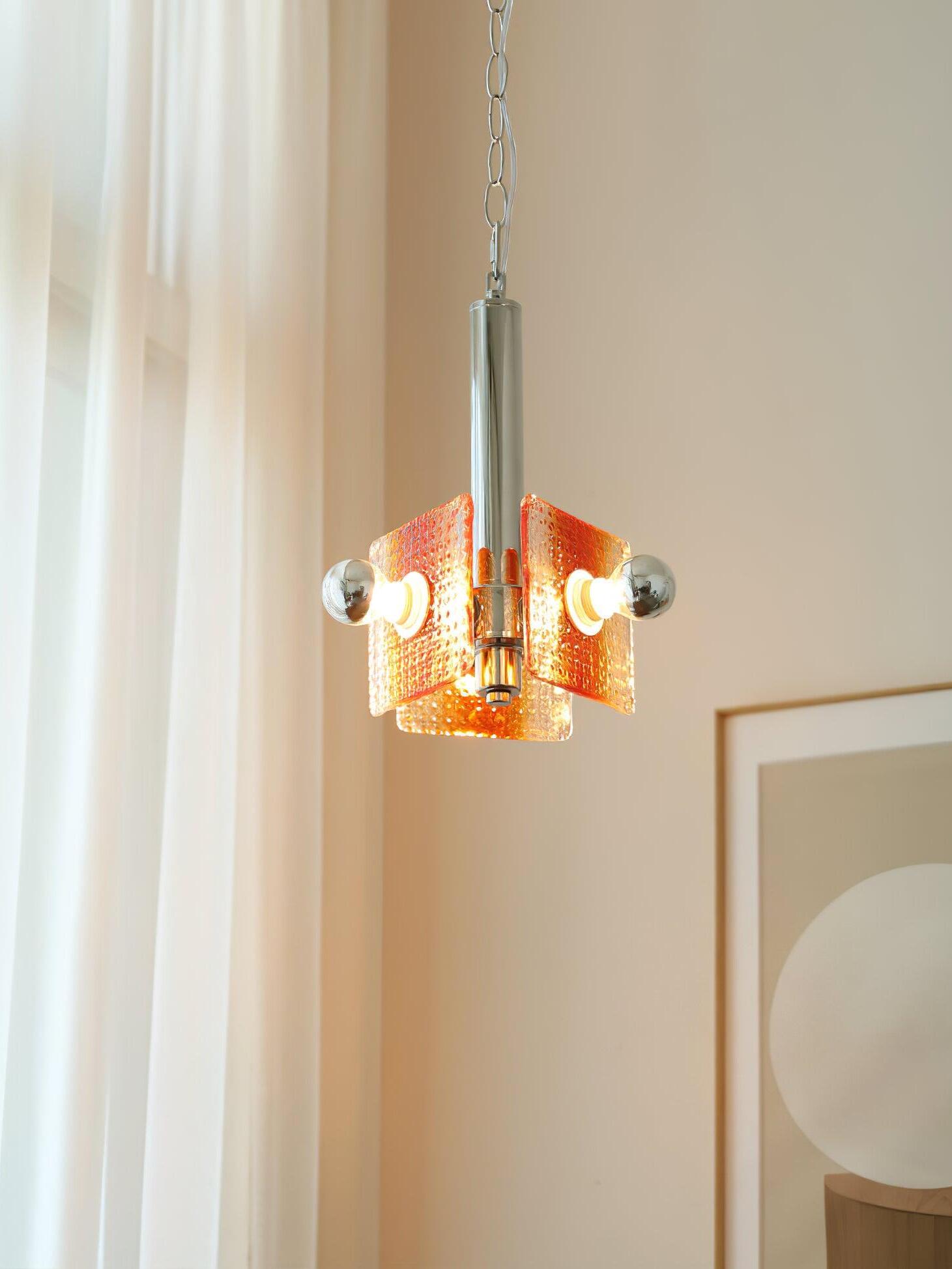 Alohi orange glass pendant glowing against a bright curtain