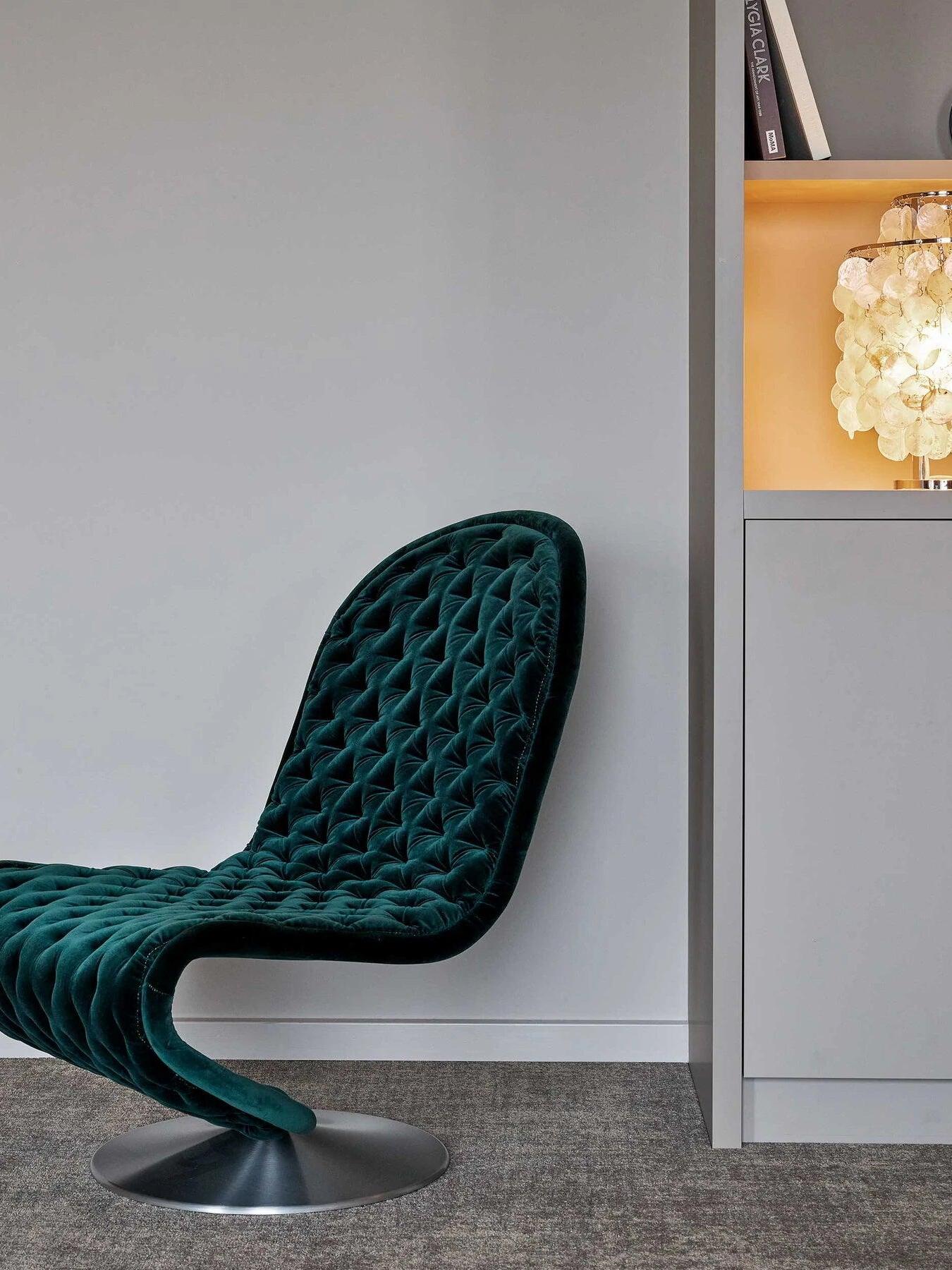 Green chair beside cabinetry and cropped hanging shell fixture
