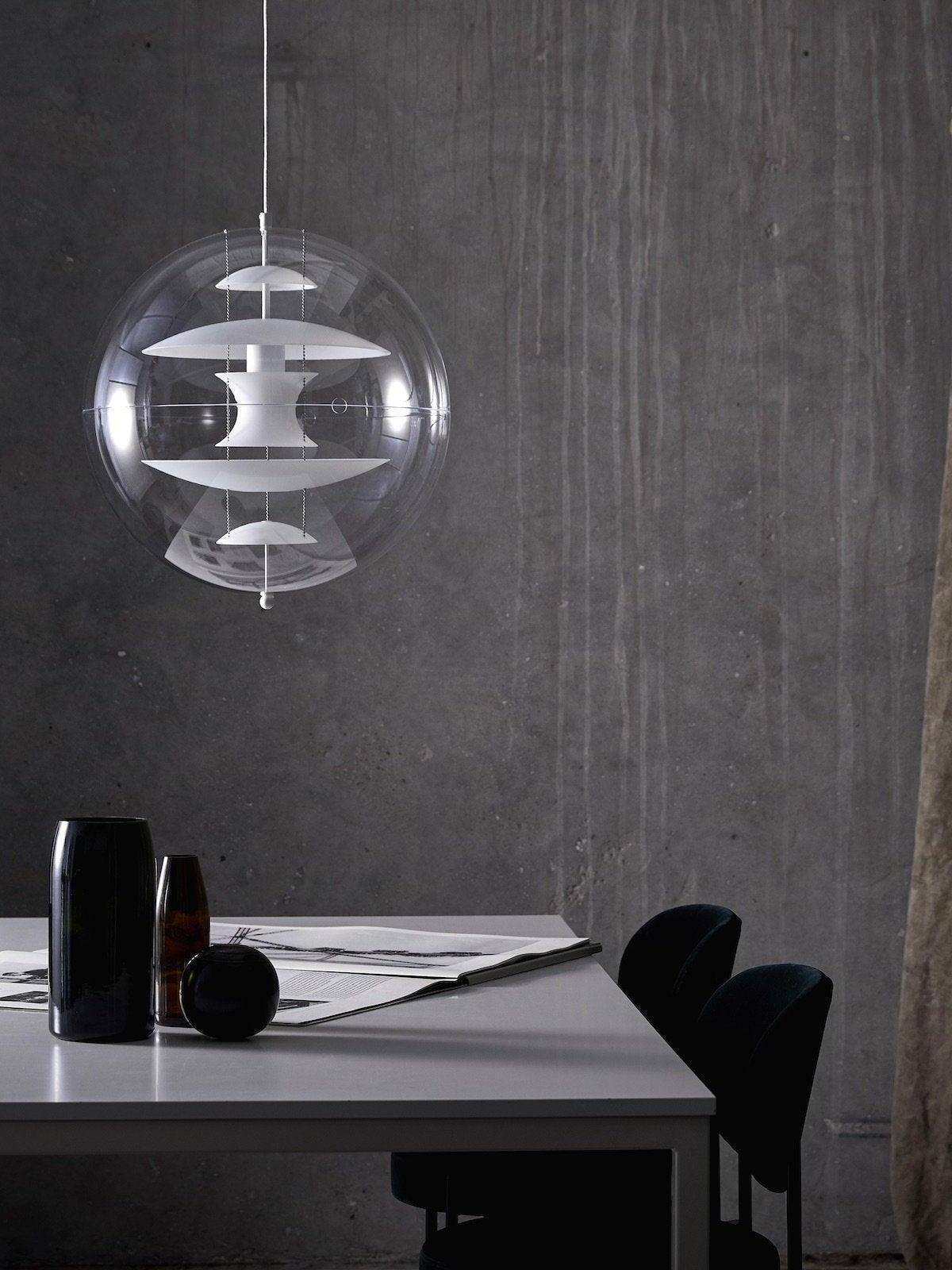 Clear globe with white internal discs and a white cord above a table with black vases