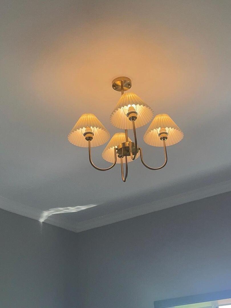 Low-angle view of an illuminated pleated-shade chandelier near a ceiling corner