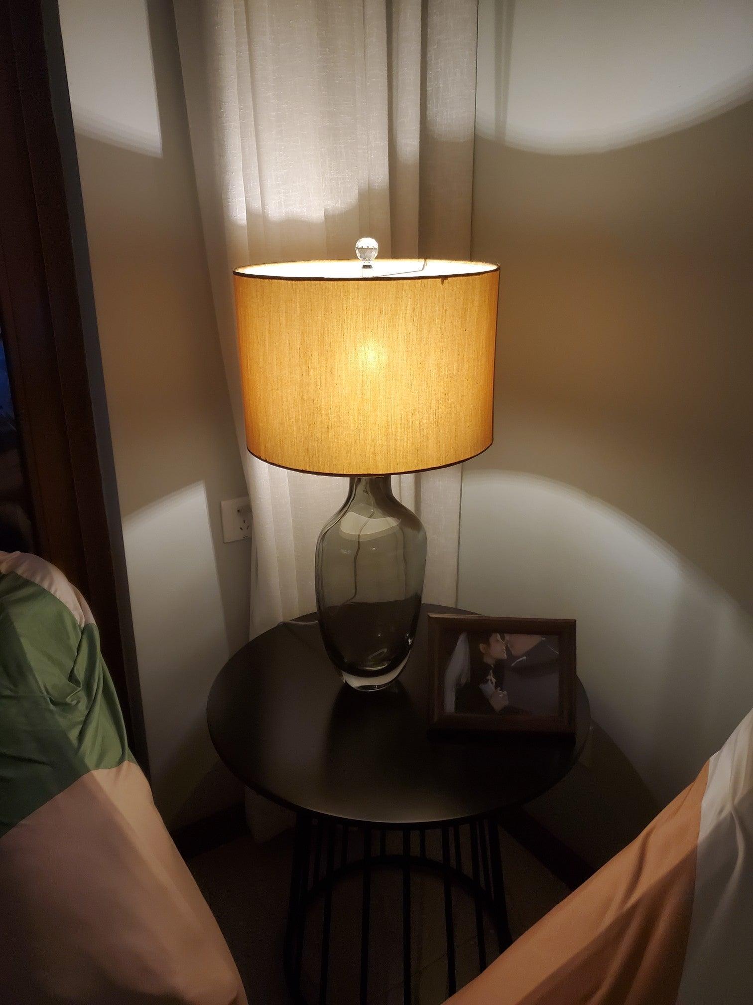 Lit table lamp beside framed photo and curtains