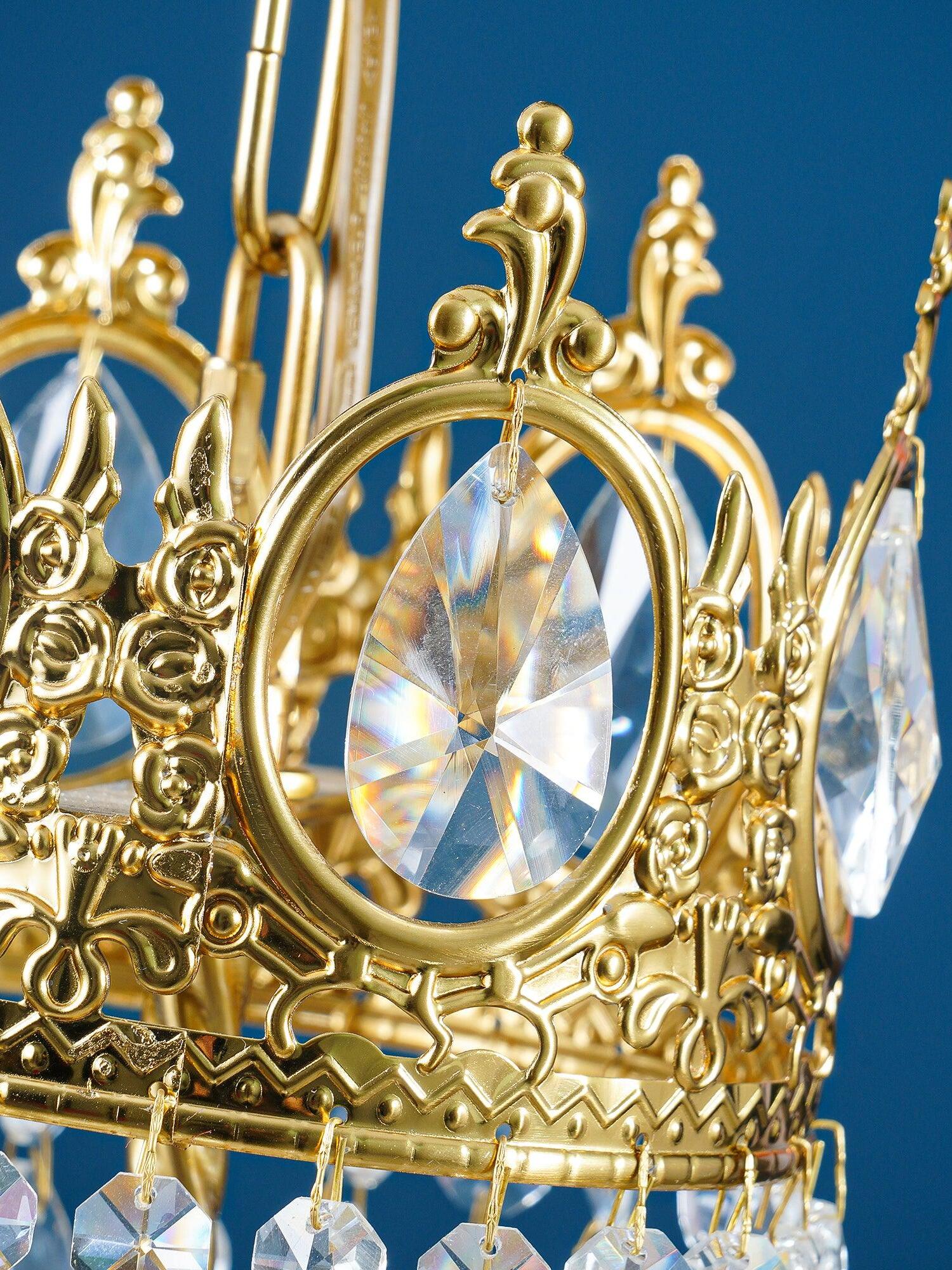 Detail of a gold-tone crown with an oval faceted crystal insert and curled ornamental metalwork