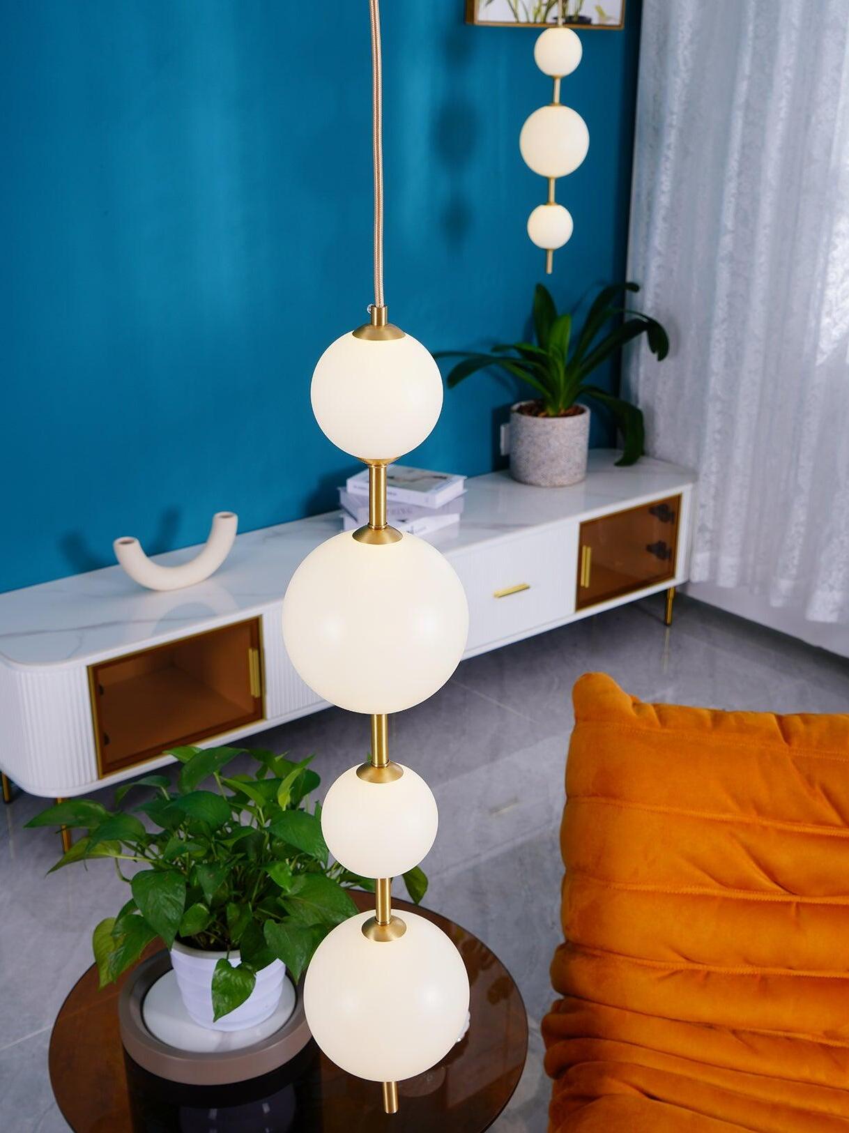 Four glowing globes in the foreground beside an orange chair, with a separate three-globe pendant behind
