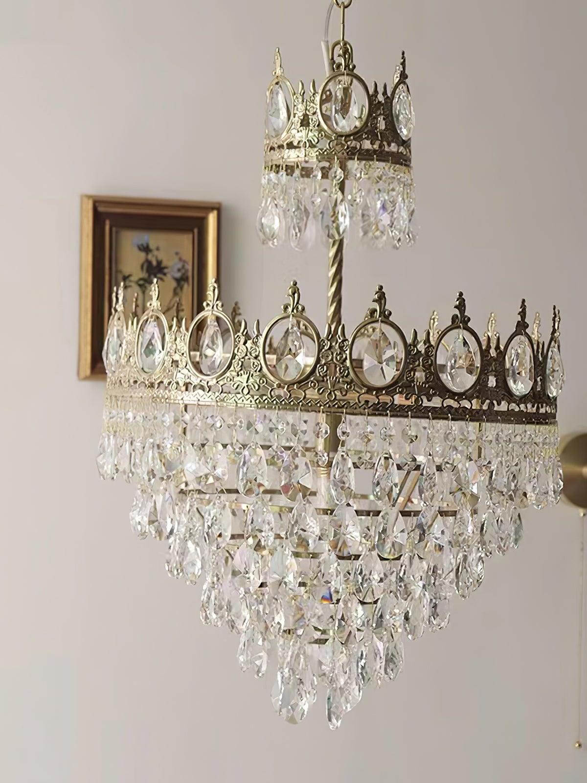 Crystal chandelier with a dark crown and clear lower drops in a bright room beside framed wall art
