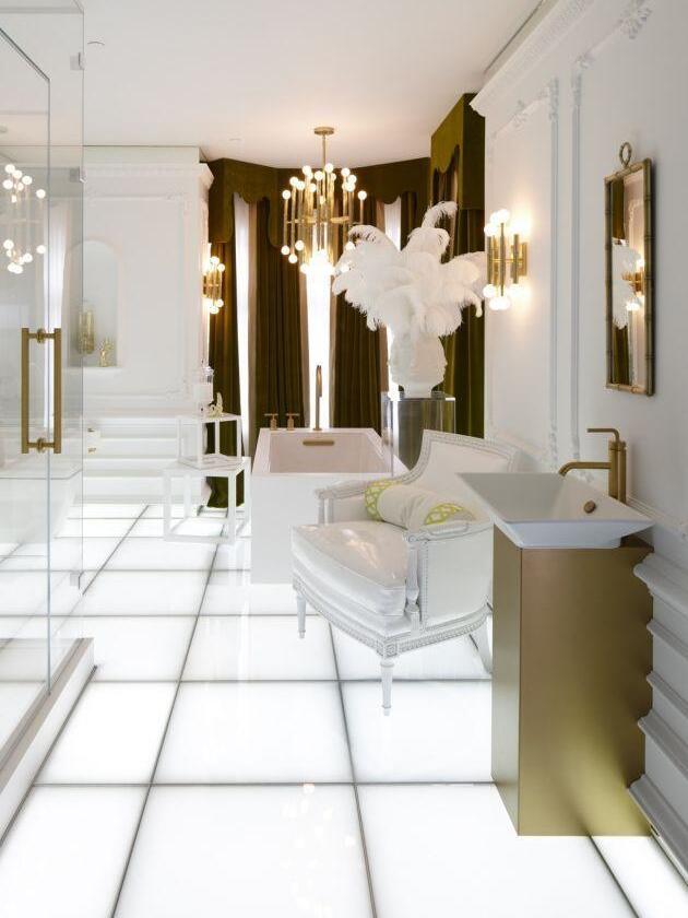Gold-tone Meurice lit on the right wall of an ornate white-and-gold bathroom with a separate ceiling chandelier
