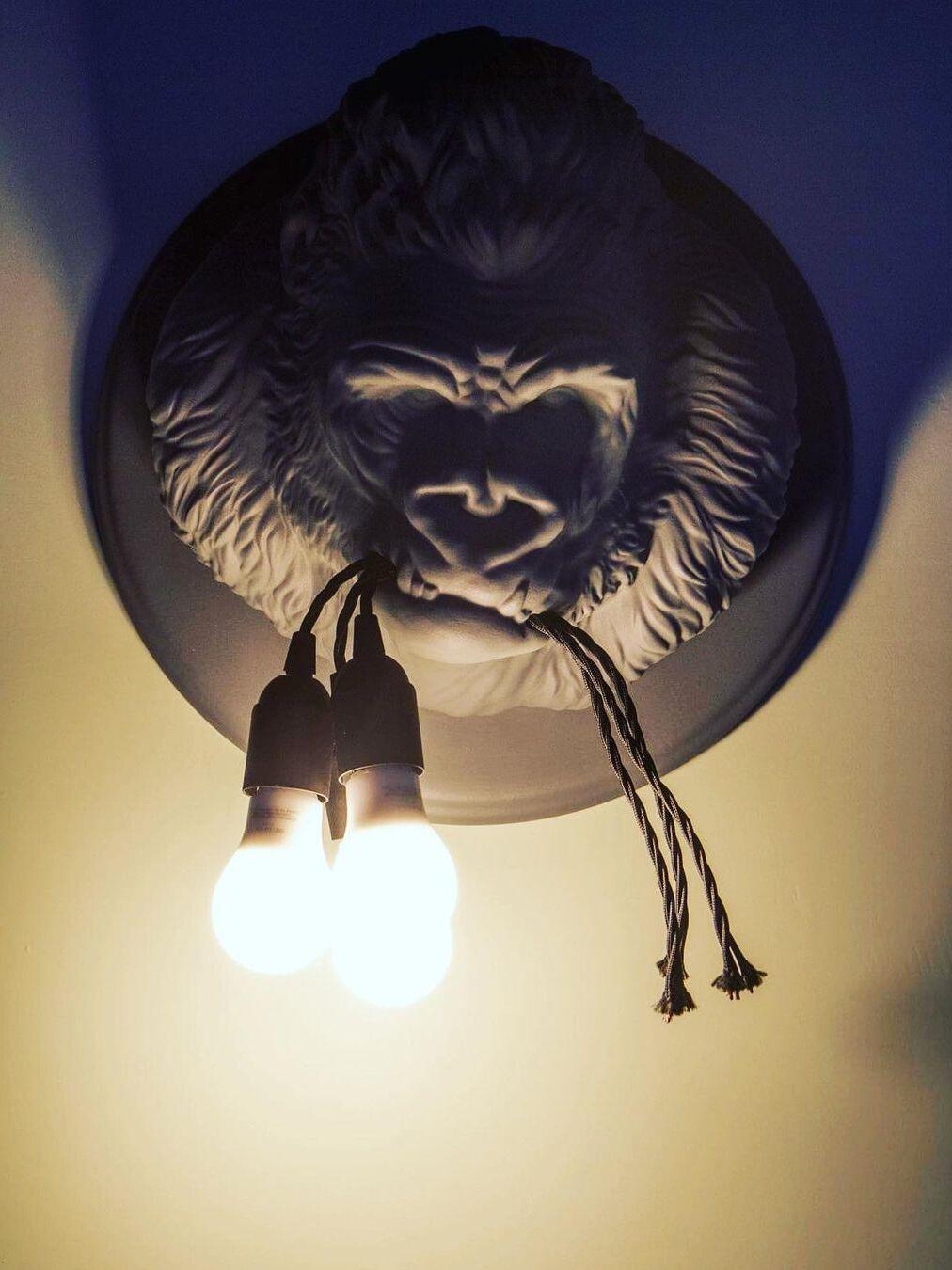 Dark gorilla face with round glowing bulbs and warm-lit backing