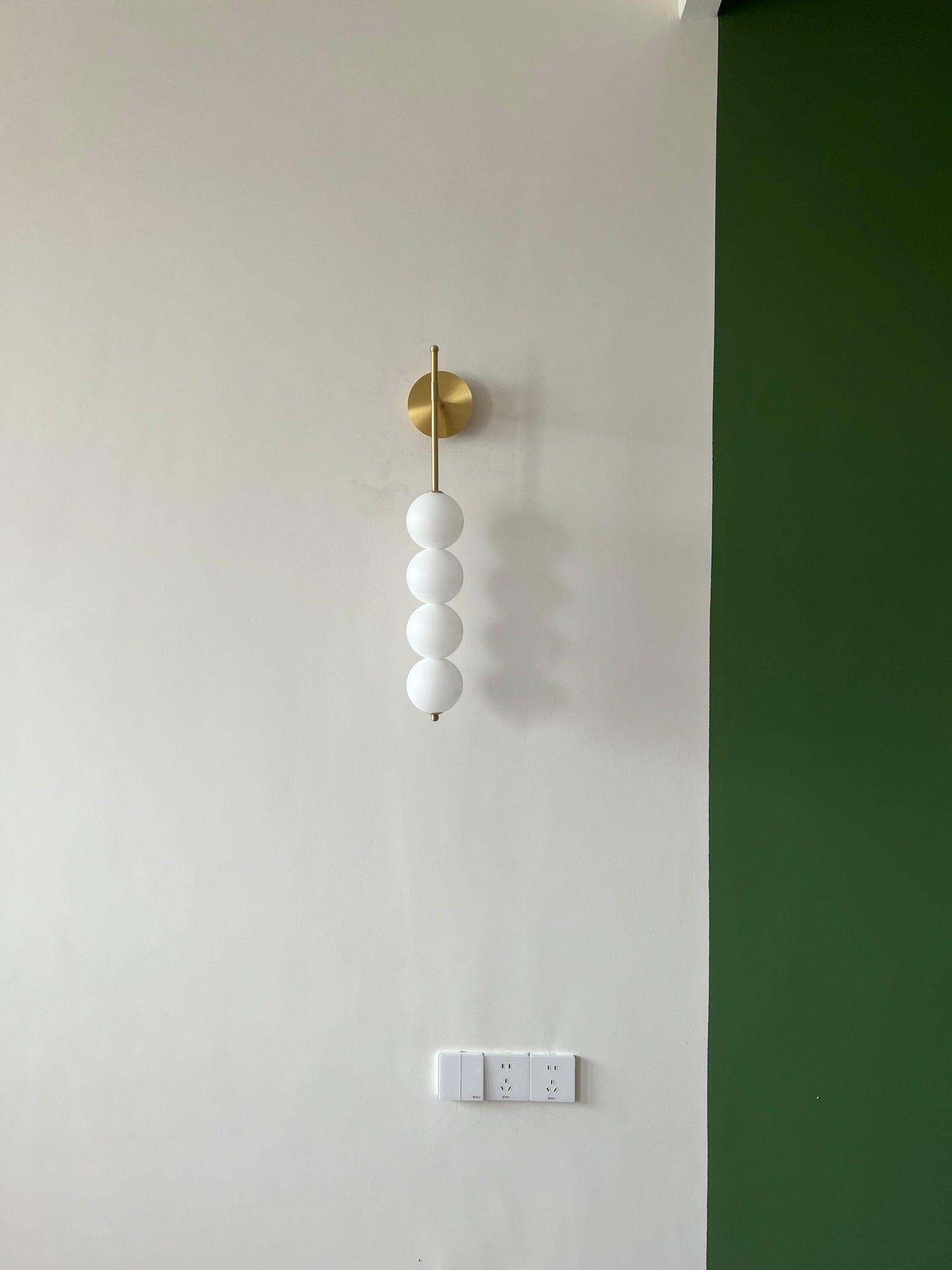 Unlit white globes on a Brass wall fitting