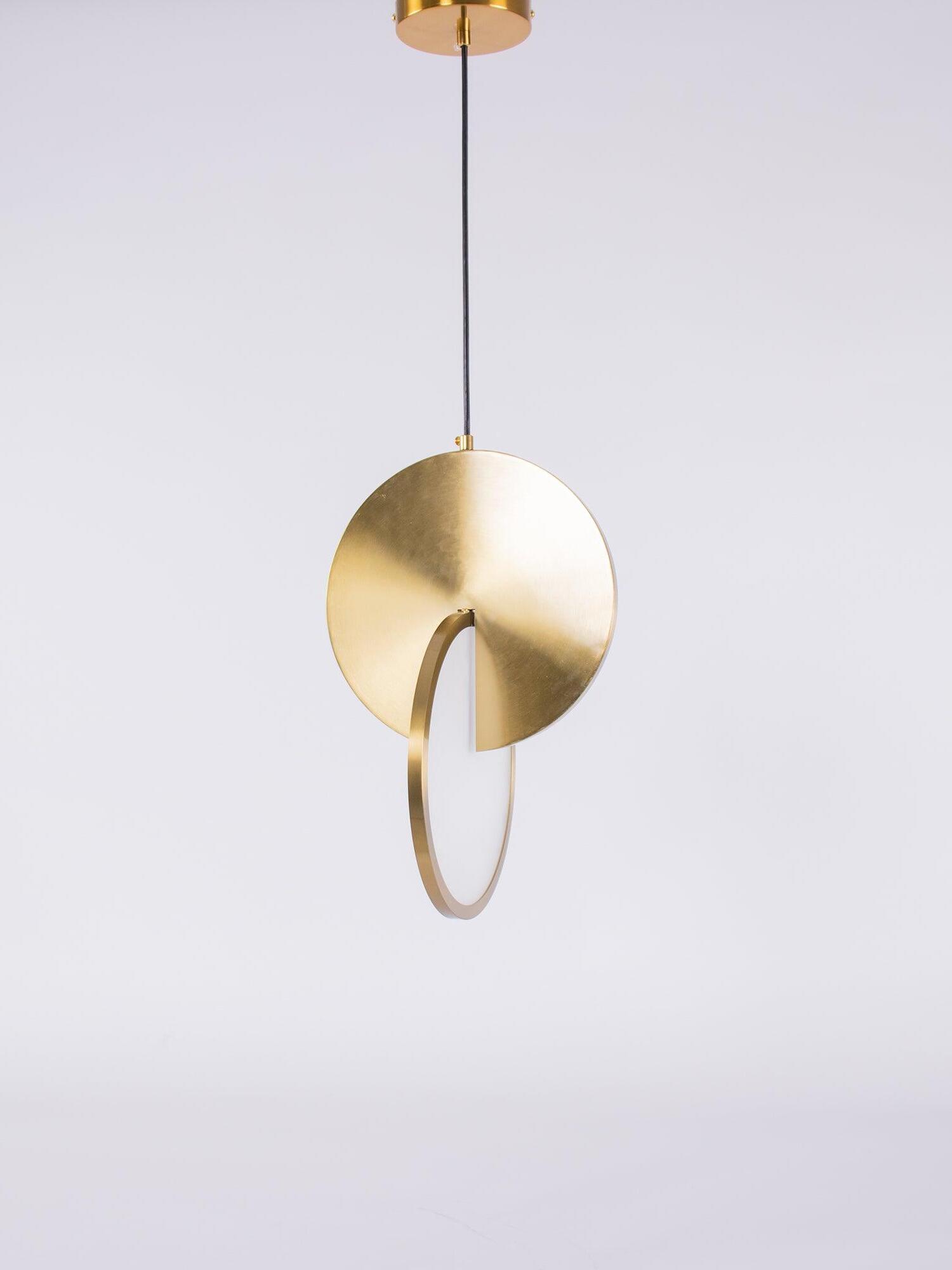 Single gold disc pendant light suspended from a round gold canopy and black cord
