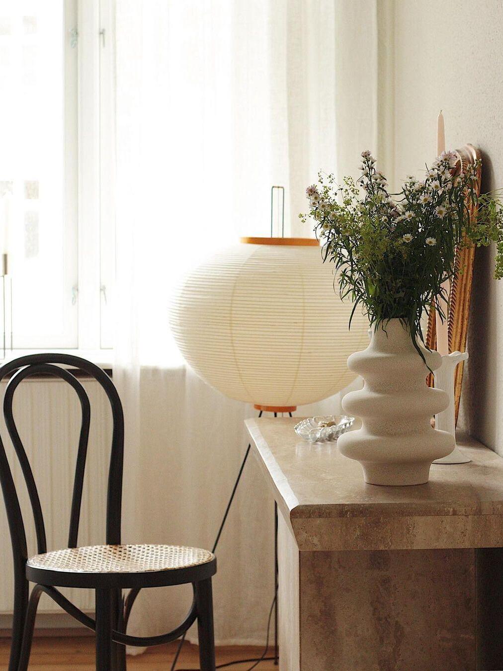 Round paper floor lamp beside a wooden desk