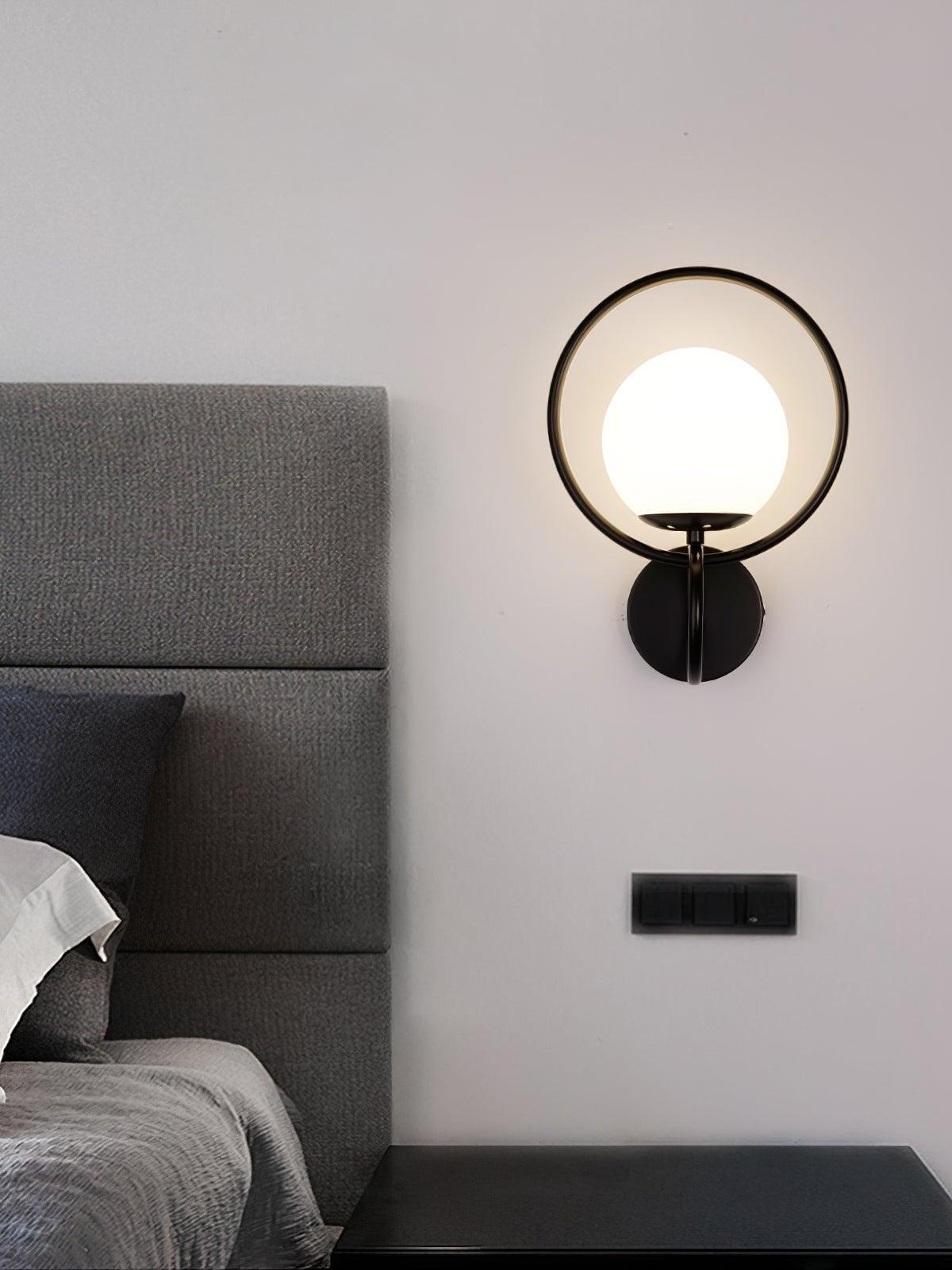 Black metal ring and white globe sconce by bed