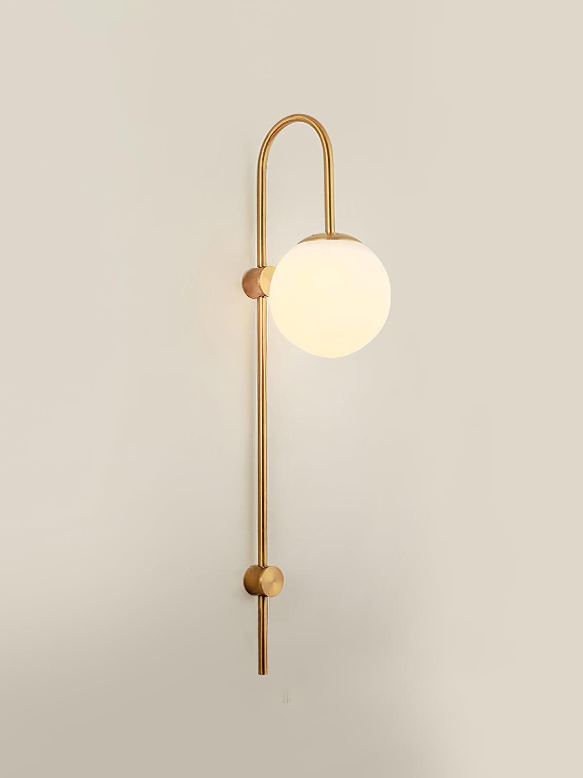 Single gold globe sconce against a pale wall