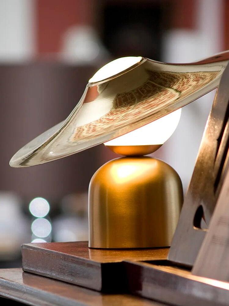 Gold disc lamp beside book on shelf