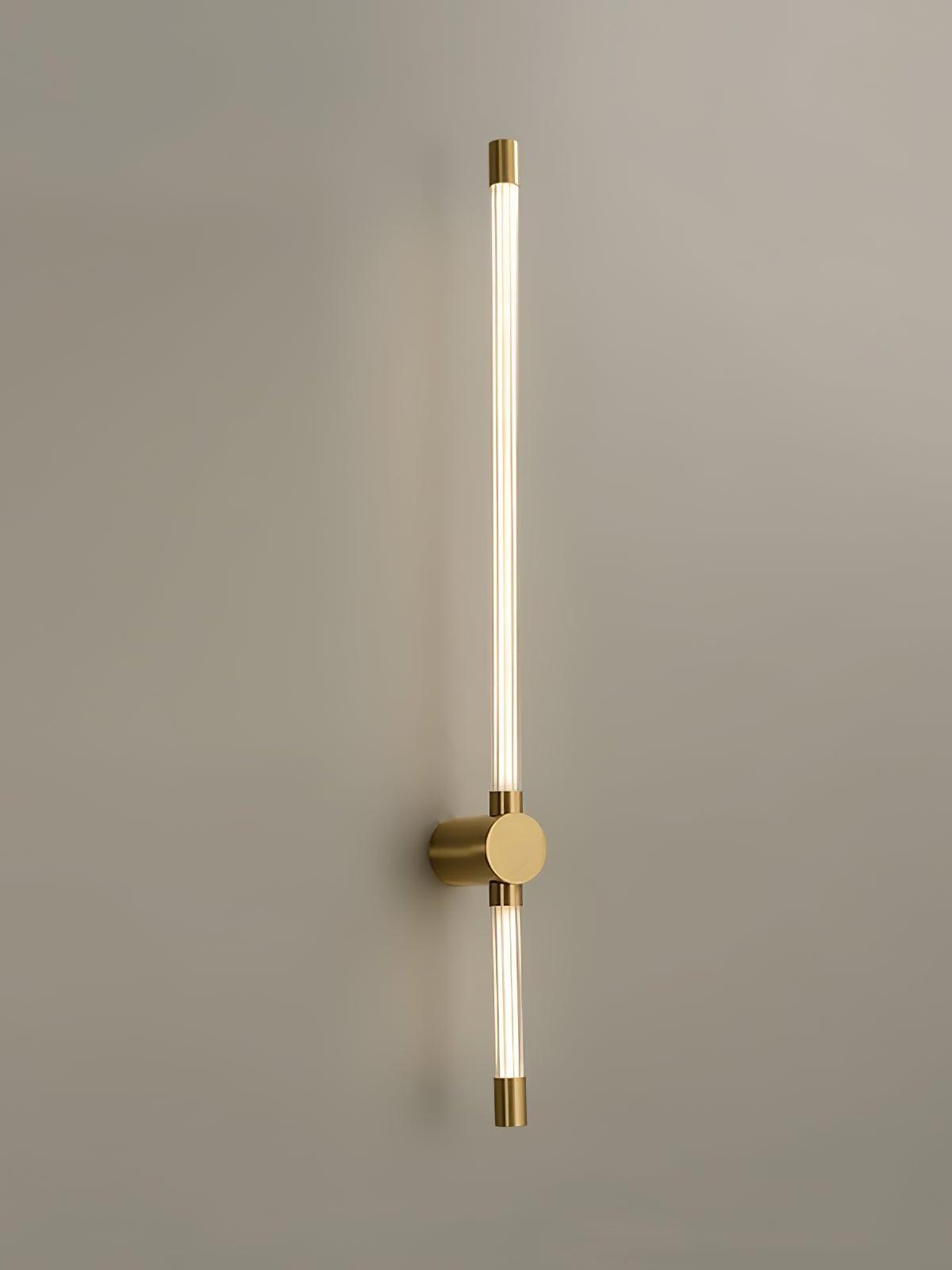 Brass-tone wall light with long upper and short lower luminous tubes around a round mount
