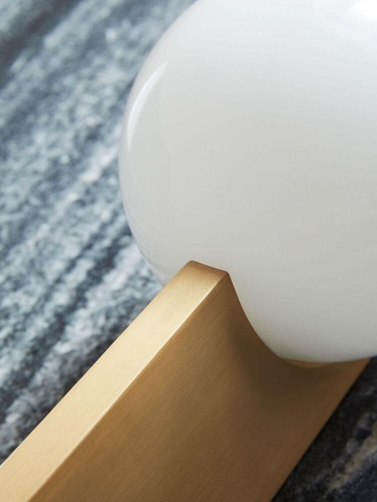 Diagonal close view of an unlit white globe beside the rounded notch of a gold-colour blade