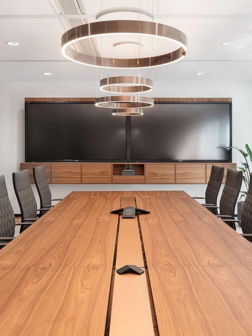 Several circular lights above a long conference table