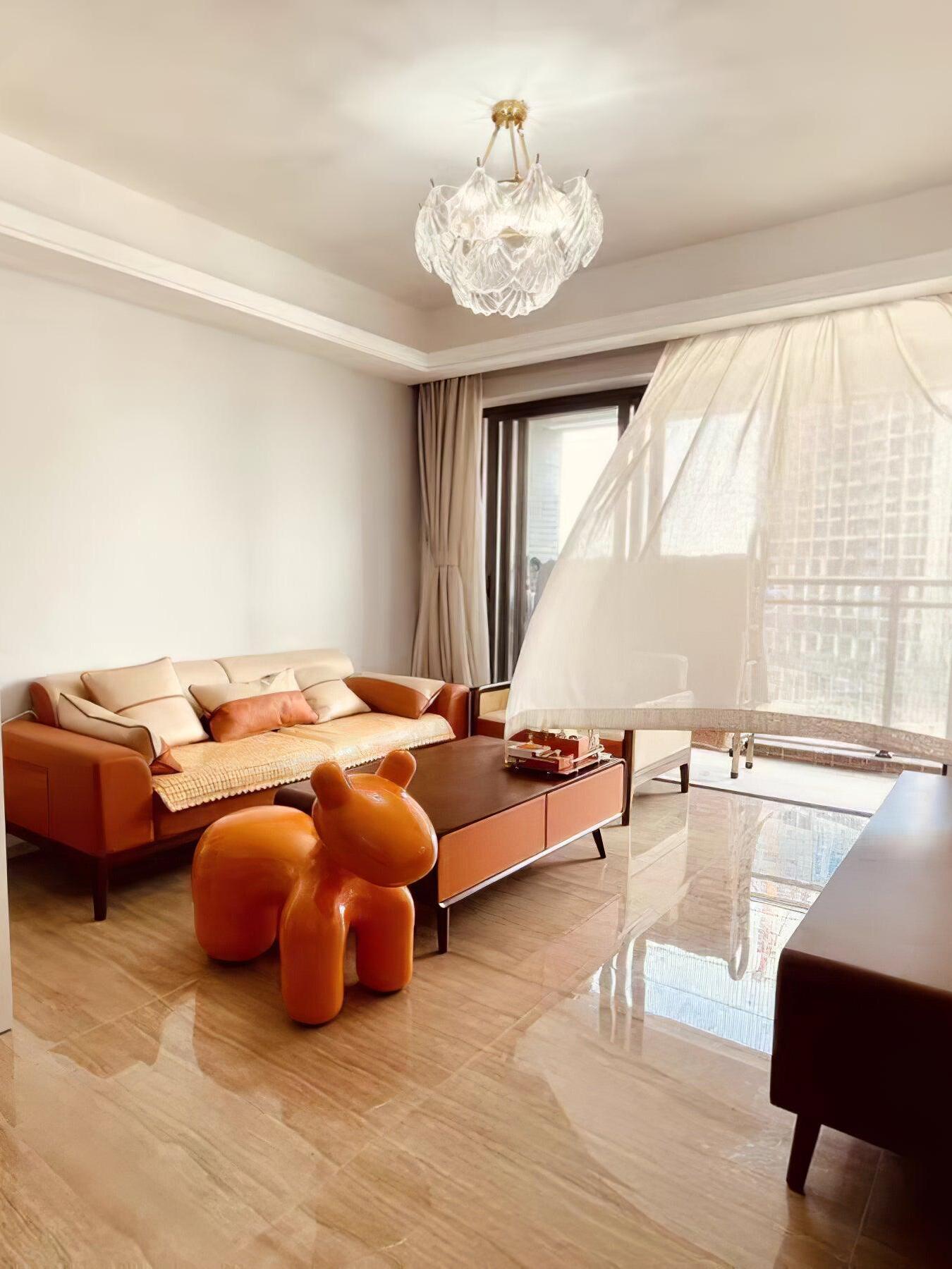Round glass ceiling light in a wood-accented room above an orange sofa beside a window