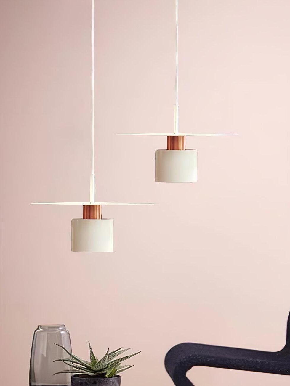 Two white disc pendants against pink wall