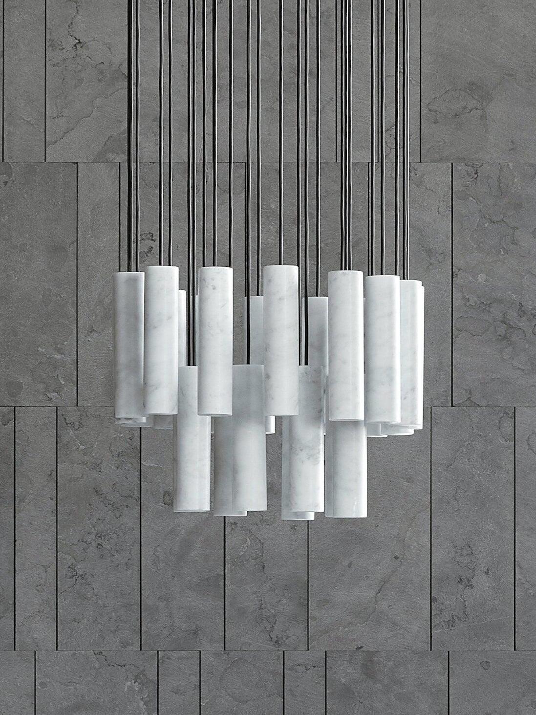 Unlit white Silo cylinders suspended at staggered heights against a grey panelled wall