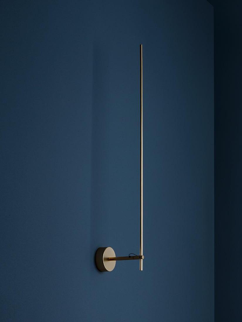 Gold Light Stick V against a Blue wall