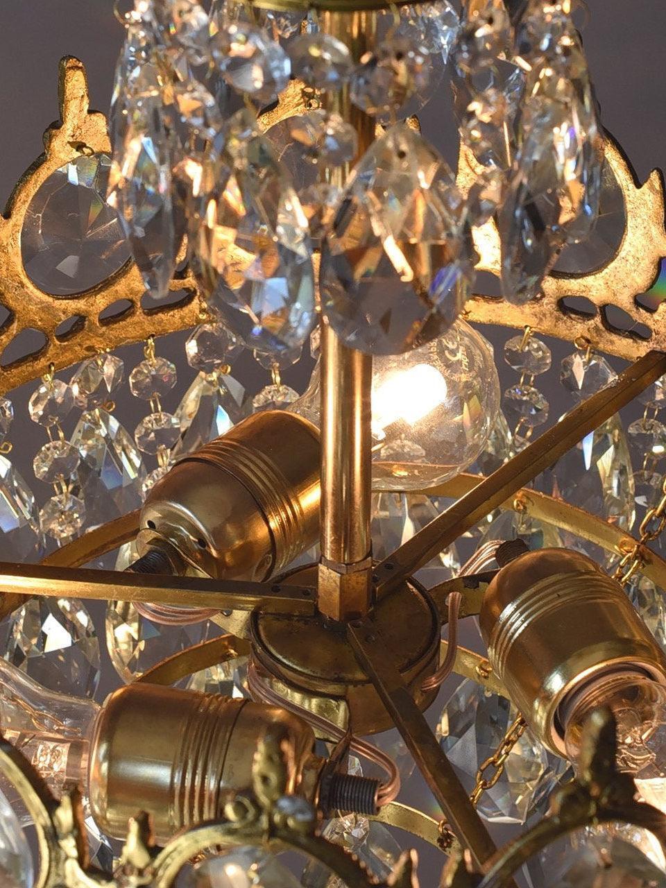 Lit chandelier interior with bulb holders and radial supports behind layered clear crystal pieces