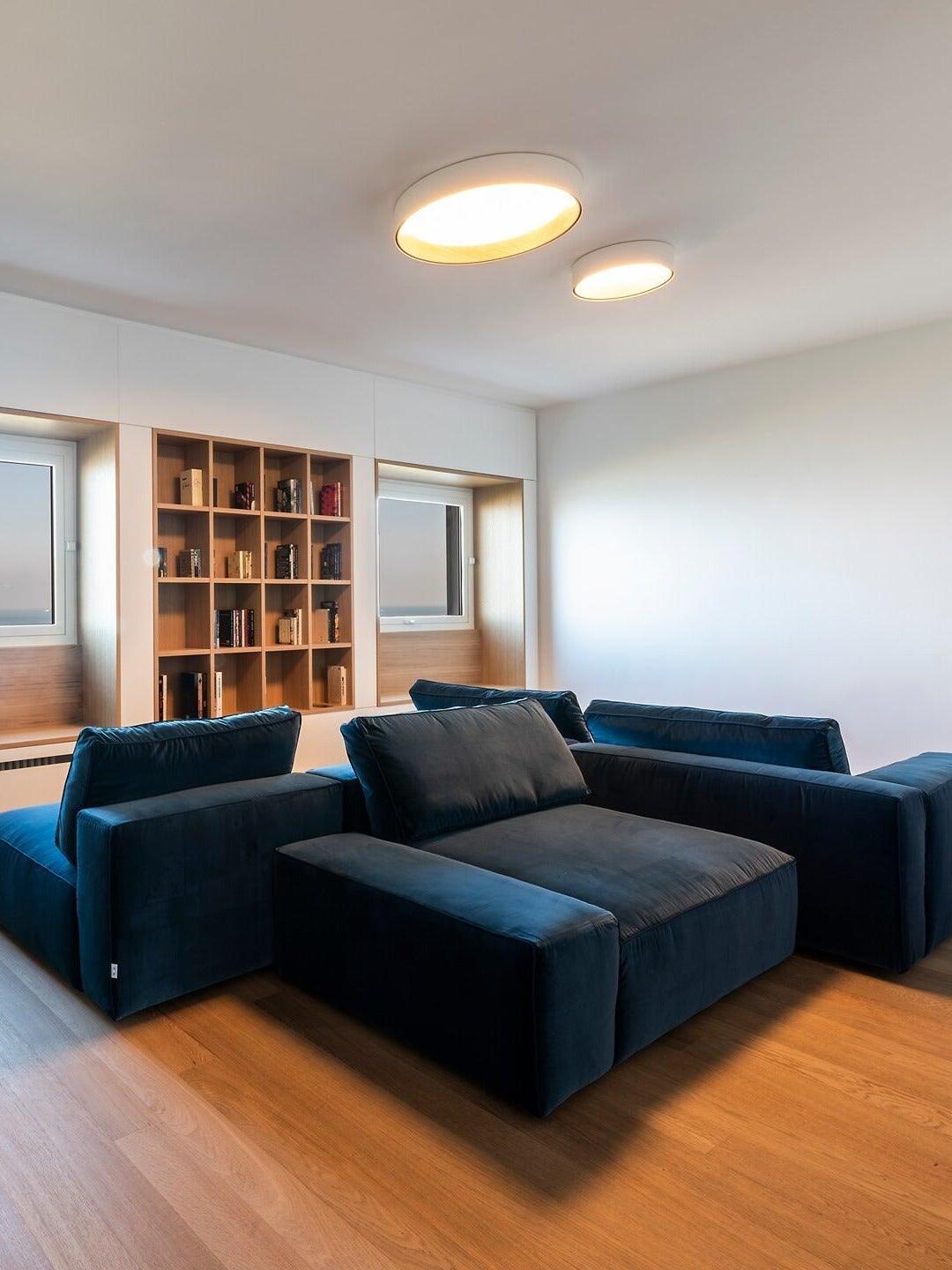 Two white round ceiling lights above blue sofa