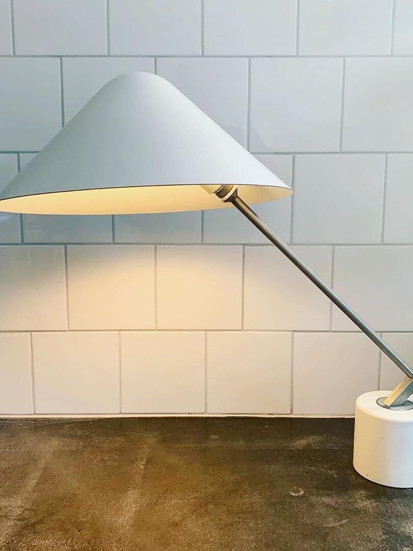 White angled shade with lit underside and silver-tone arm beside a tiled wall