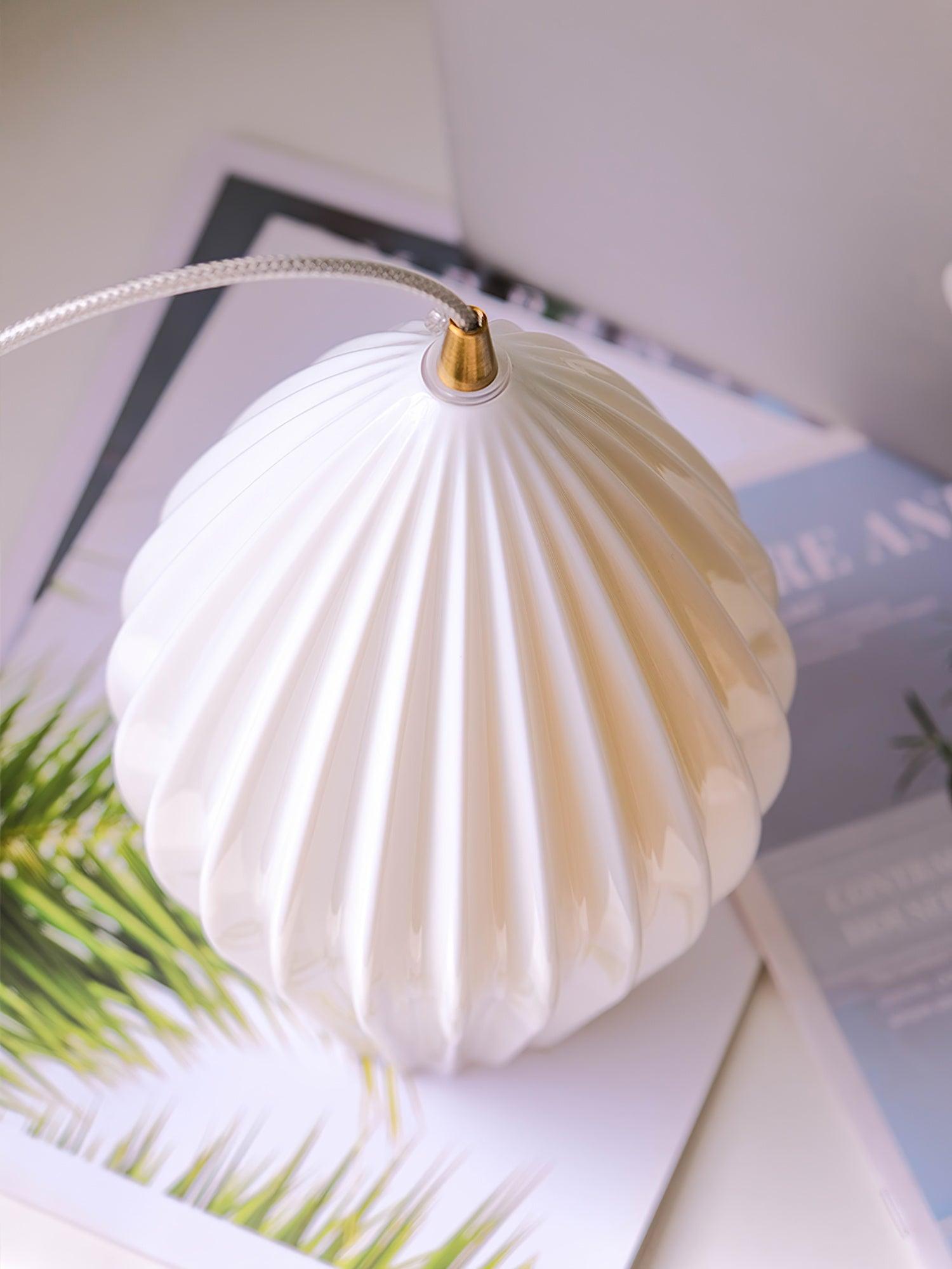 Angled overhead view of a white ribbed shade and its gold-tone cord fitting