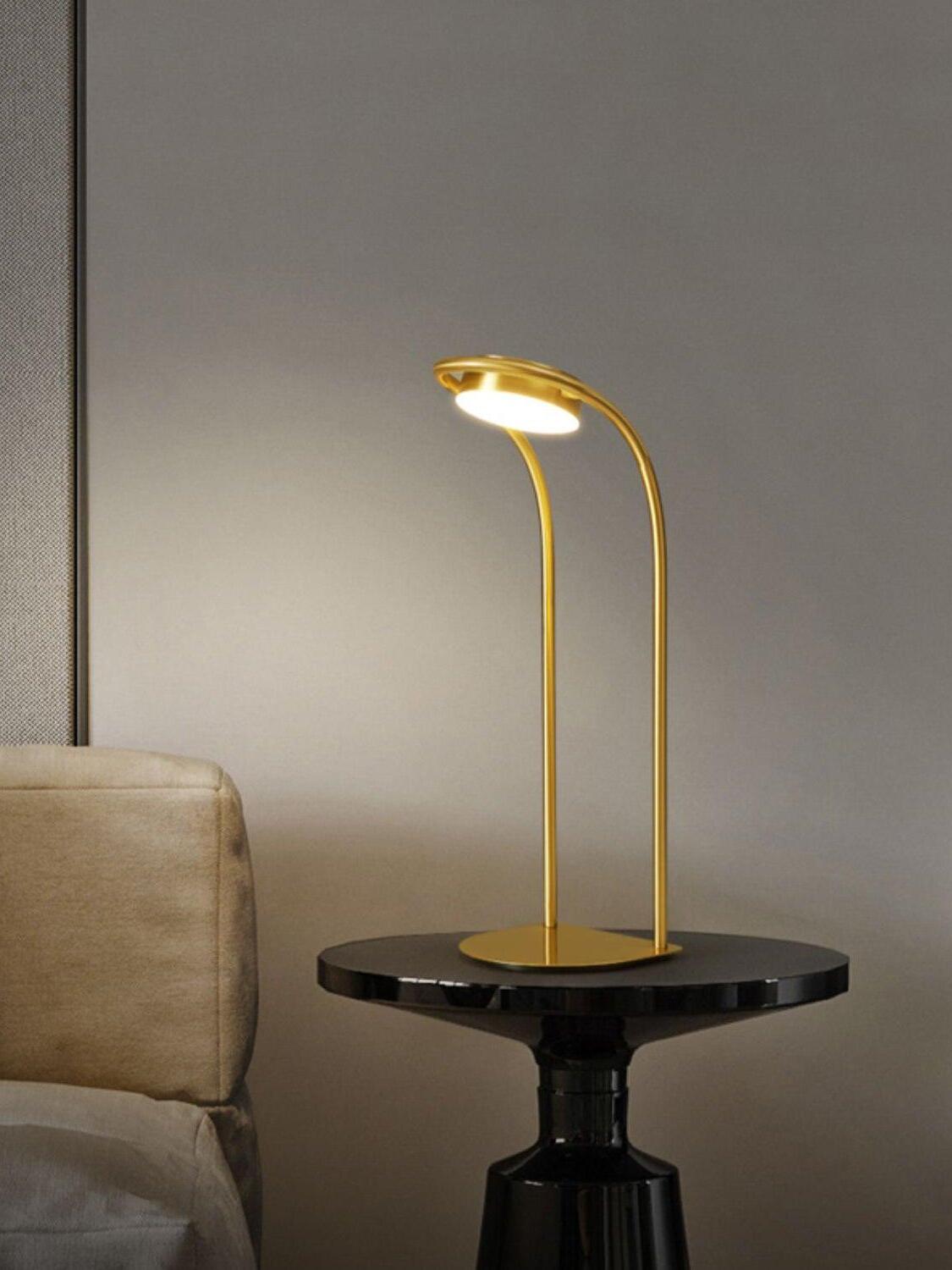 Forward-curved brass lamp on black round side table