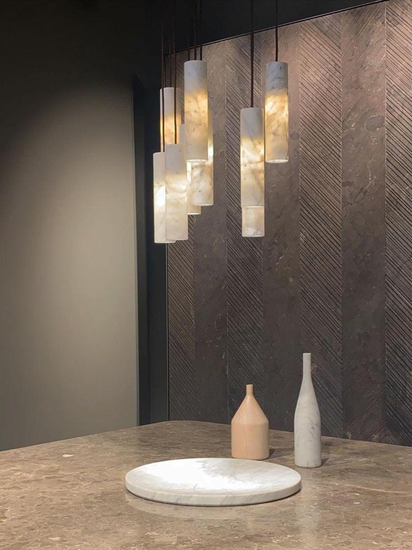 Staggered glowing Silo cylinders beside a dark wall above a pale plate and small vases