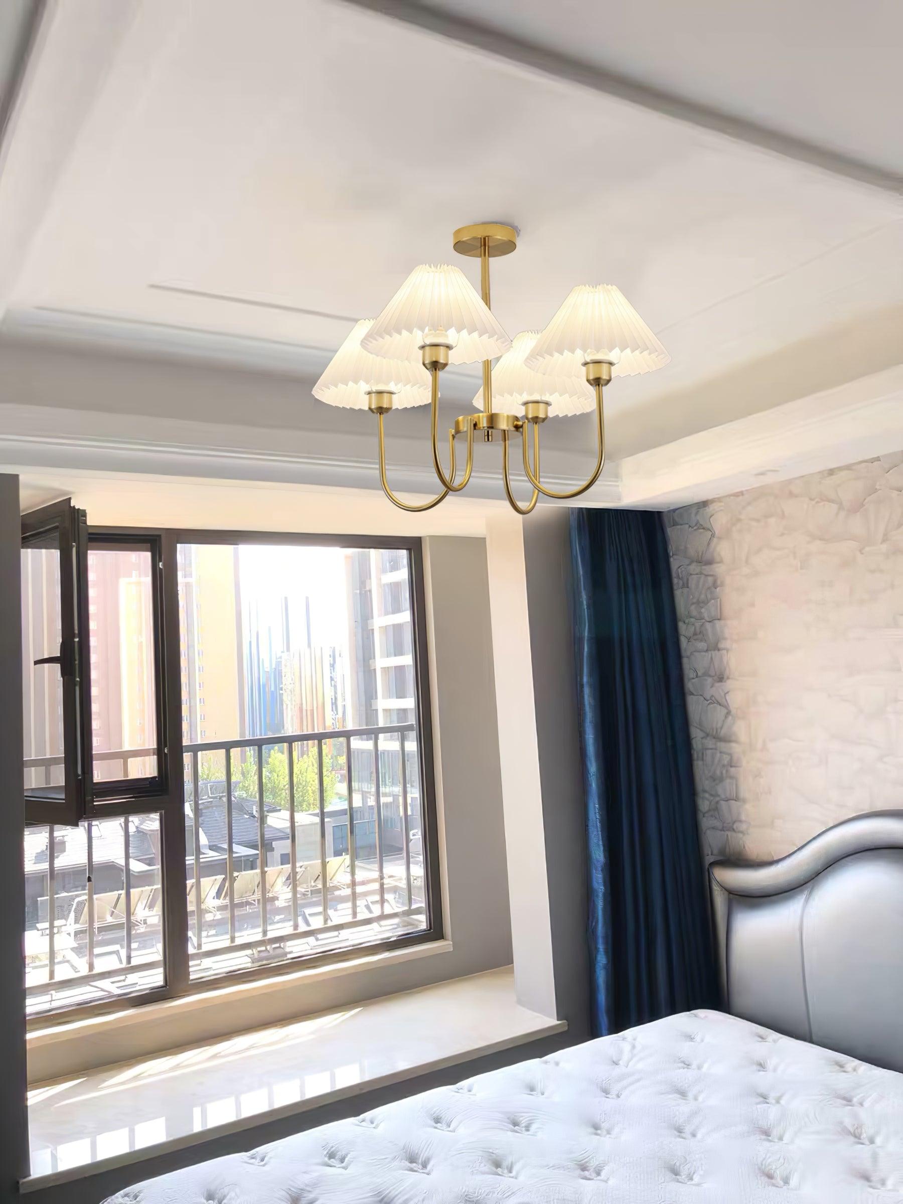 Chandelier above a bed beside an open window and dark curtains