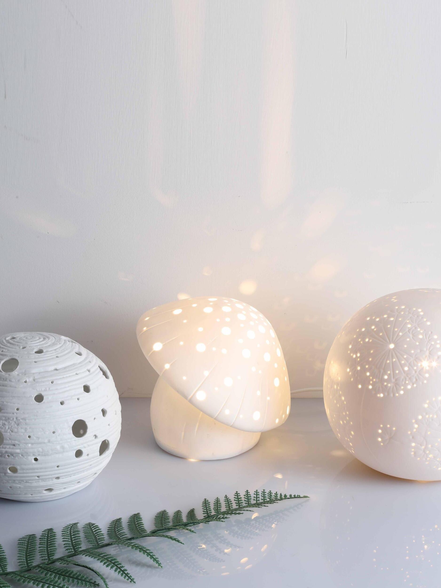 Fungo mushroom lamp displayed between two round perforated lamps beside a green leaf