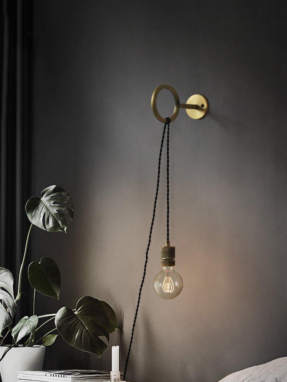 Hanging globe bulb from loop bracket beside plant and bed