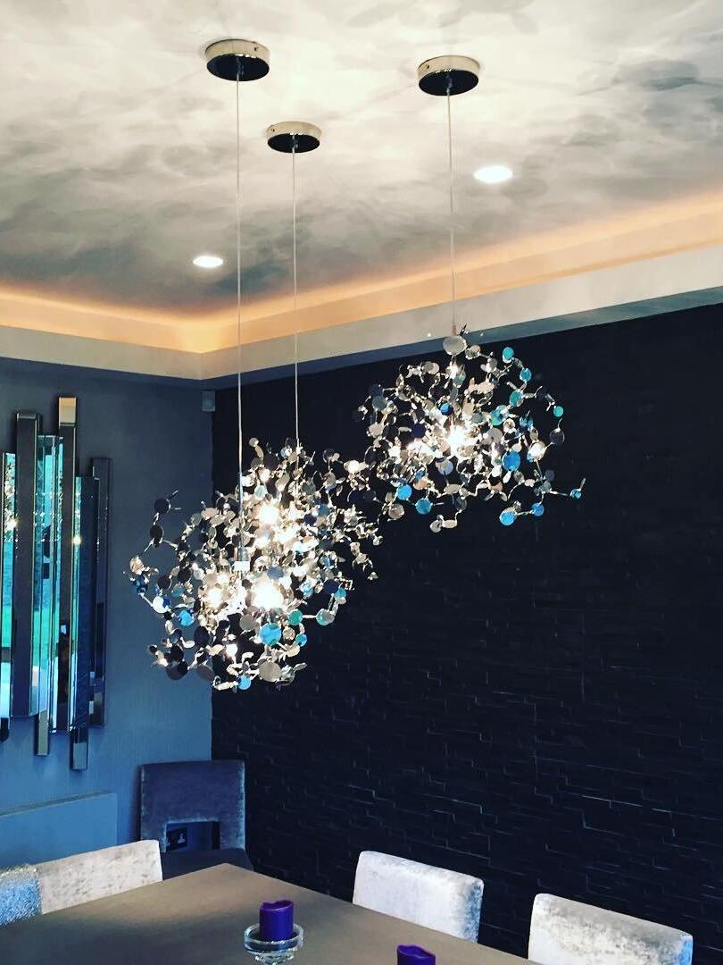Silver disc chandelier above a table in a dark dining room