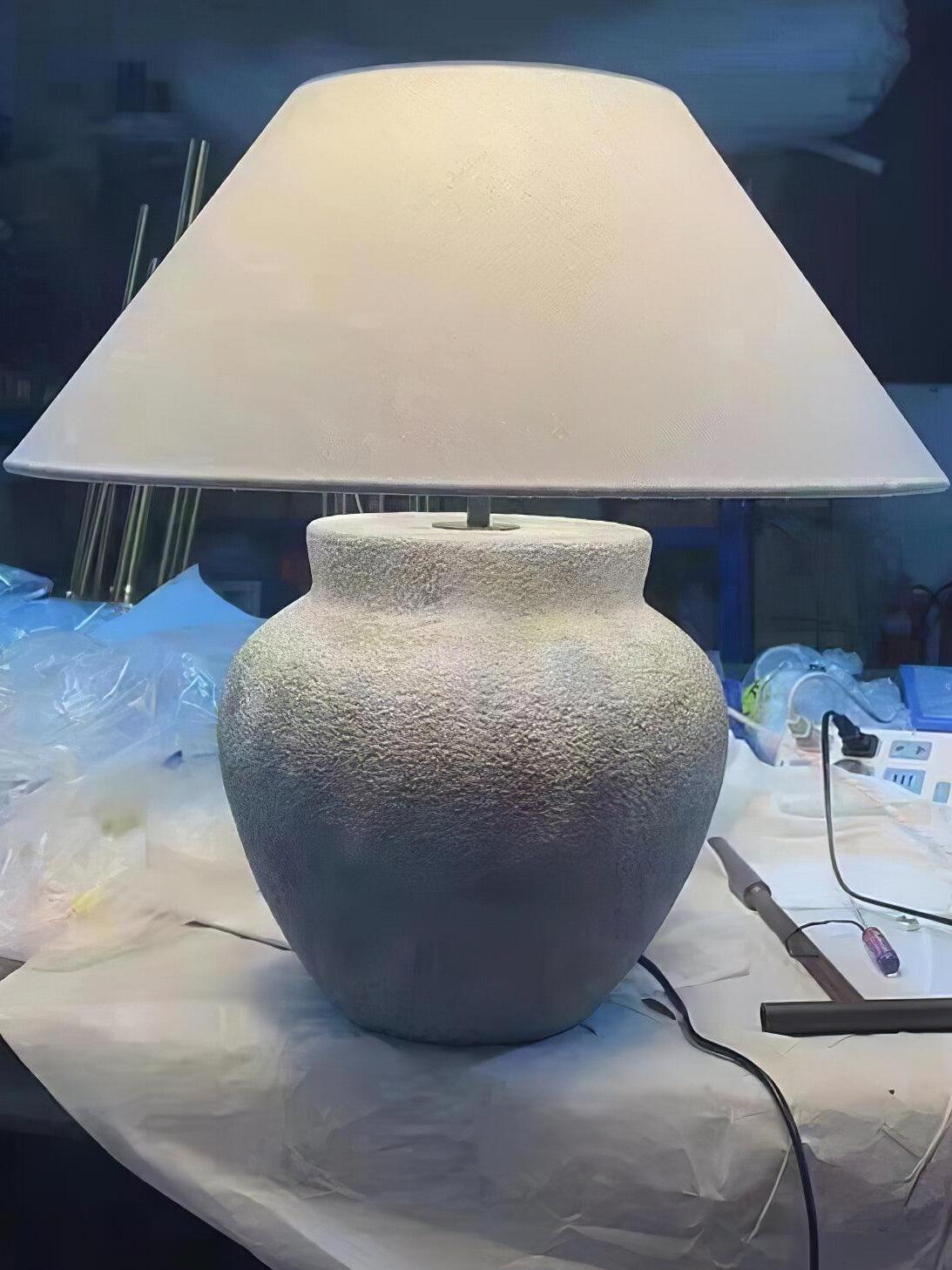 Pale urn lamp with cord on covered work surface