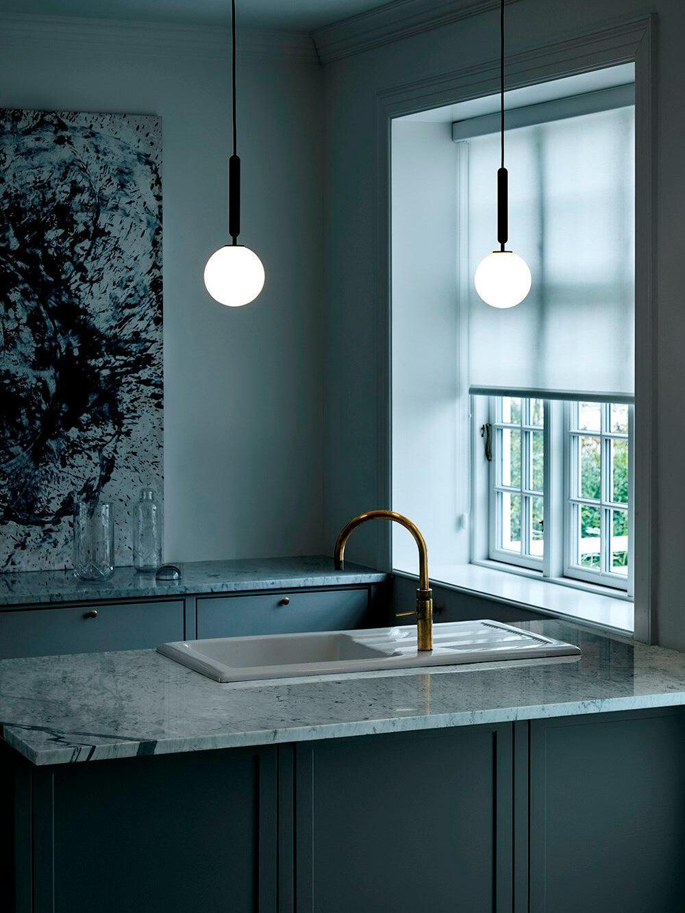 White single globes pictured above a sink counter