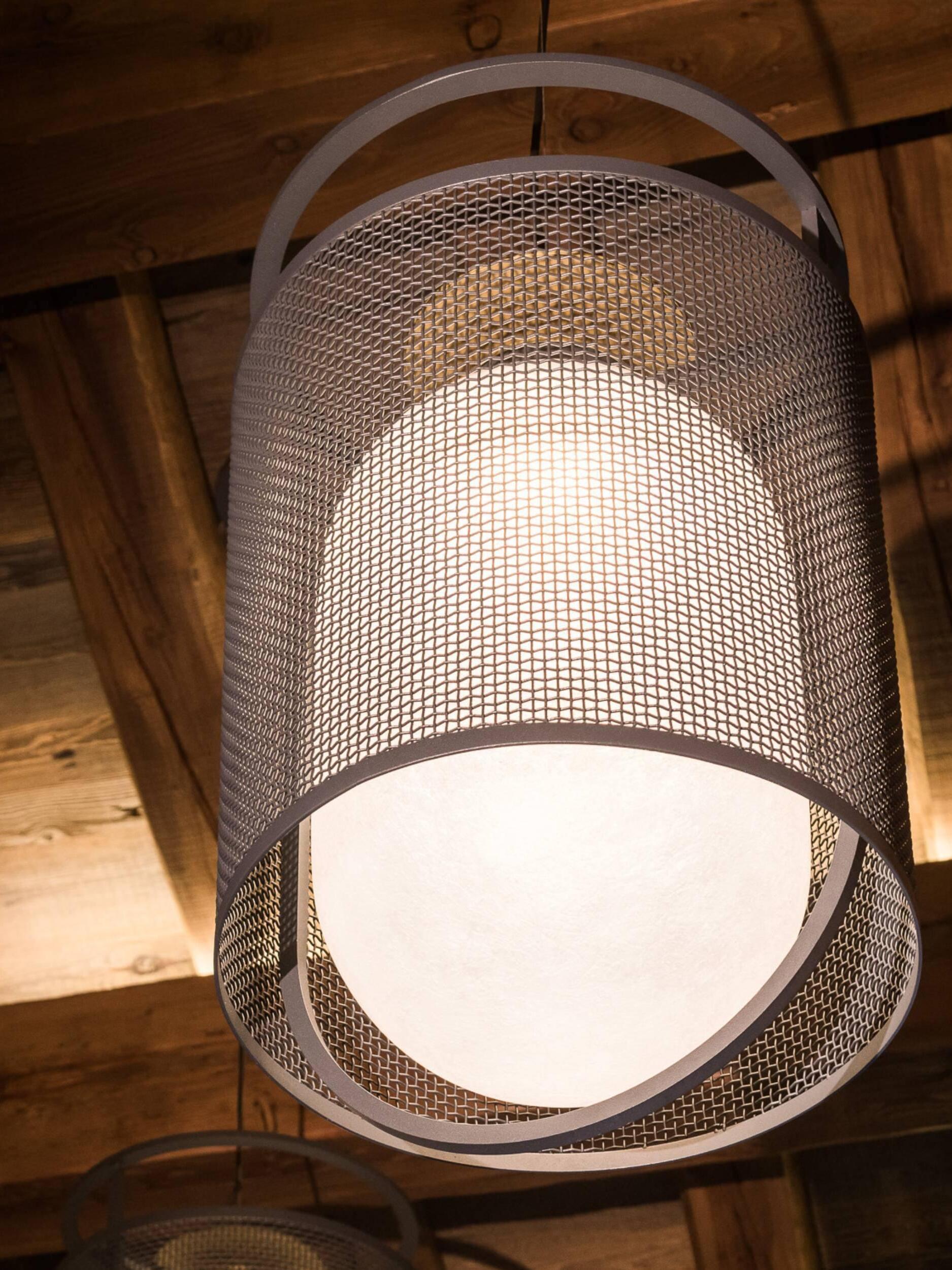 Low view of glowing mesh lantern beneath timber rafters