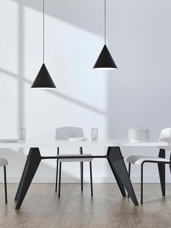 Two black cone pendants above a white table with black legs, white chairs, glasses and stacked dishes