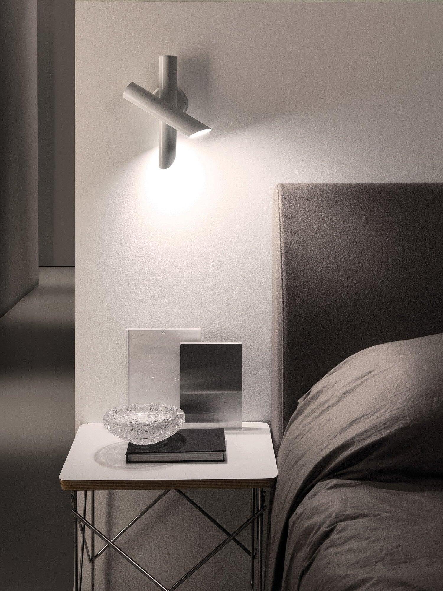 White crossed-tube lamp above bedroom side table