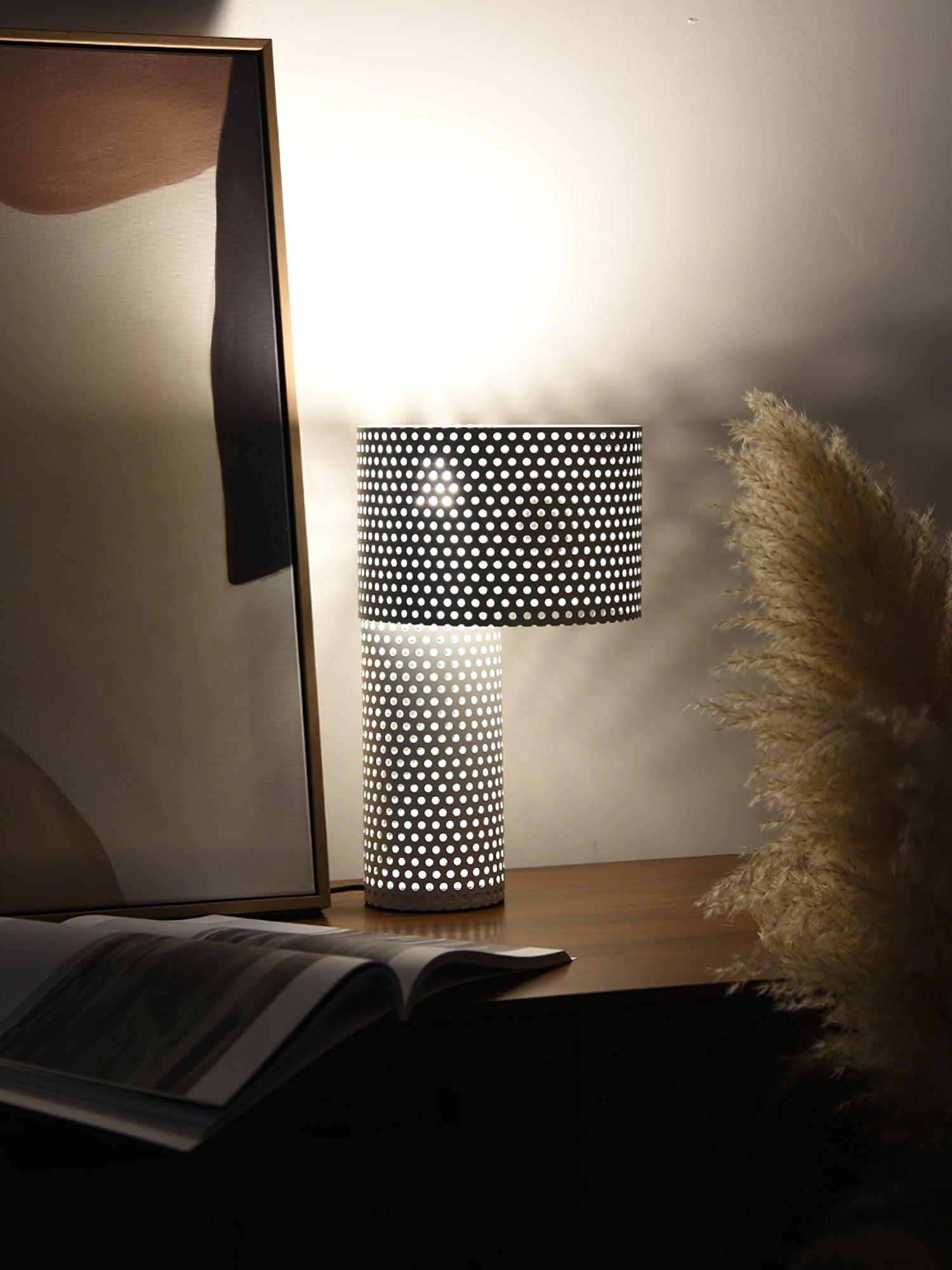 White perforated lamp beside mirror and open book
