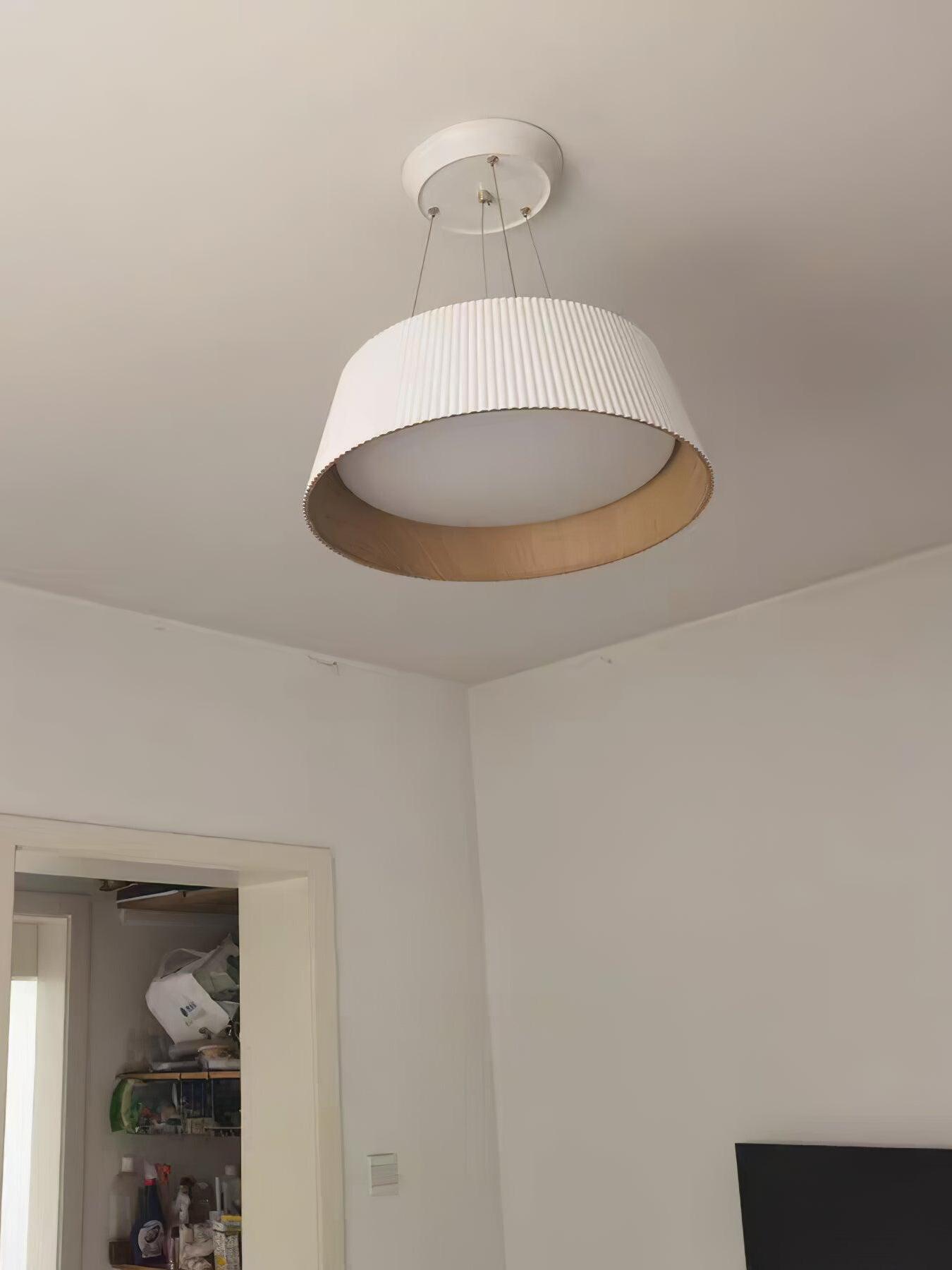 White ribbed pendant with short suspension viewed from below near a doorway, showing recessed circular diffuser
