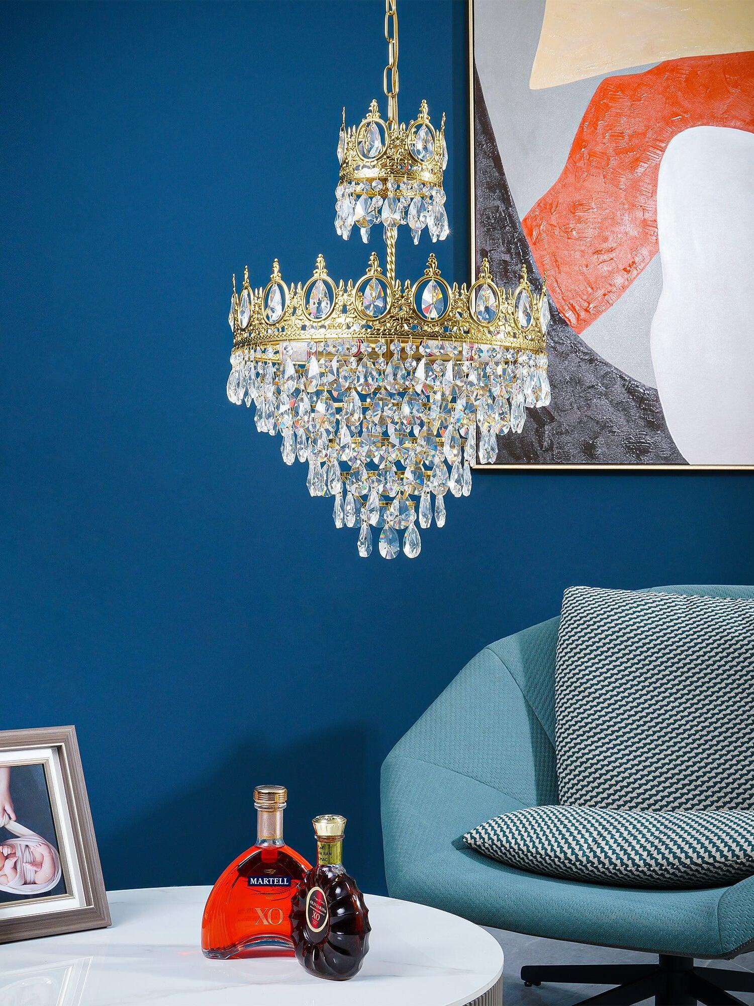 Crystal chandelier beside a teal chair against a blue wall, with a framed photo on the side table