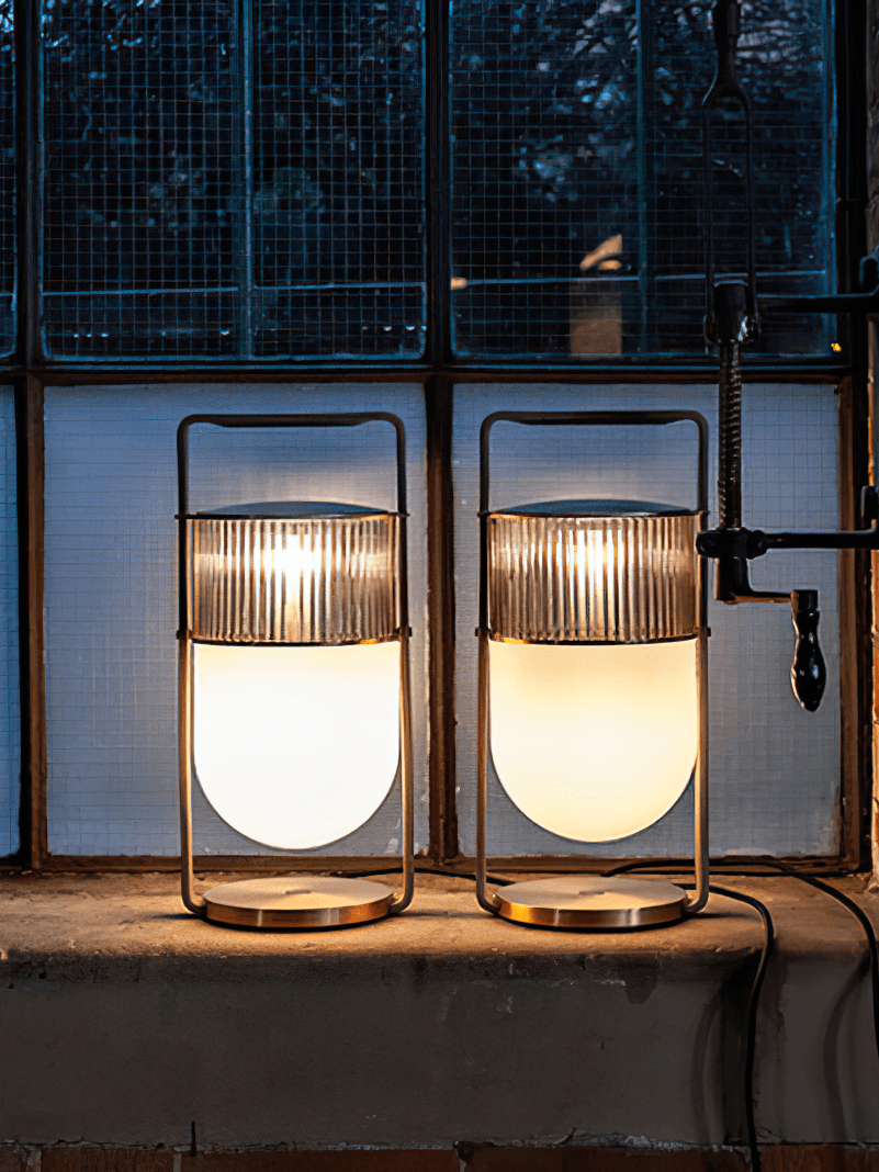 Two illuminated Xi lamps with clear ribbed glass on a window ledge, showing different photographed light colours