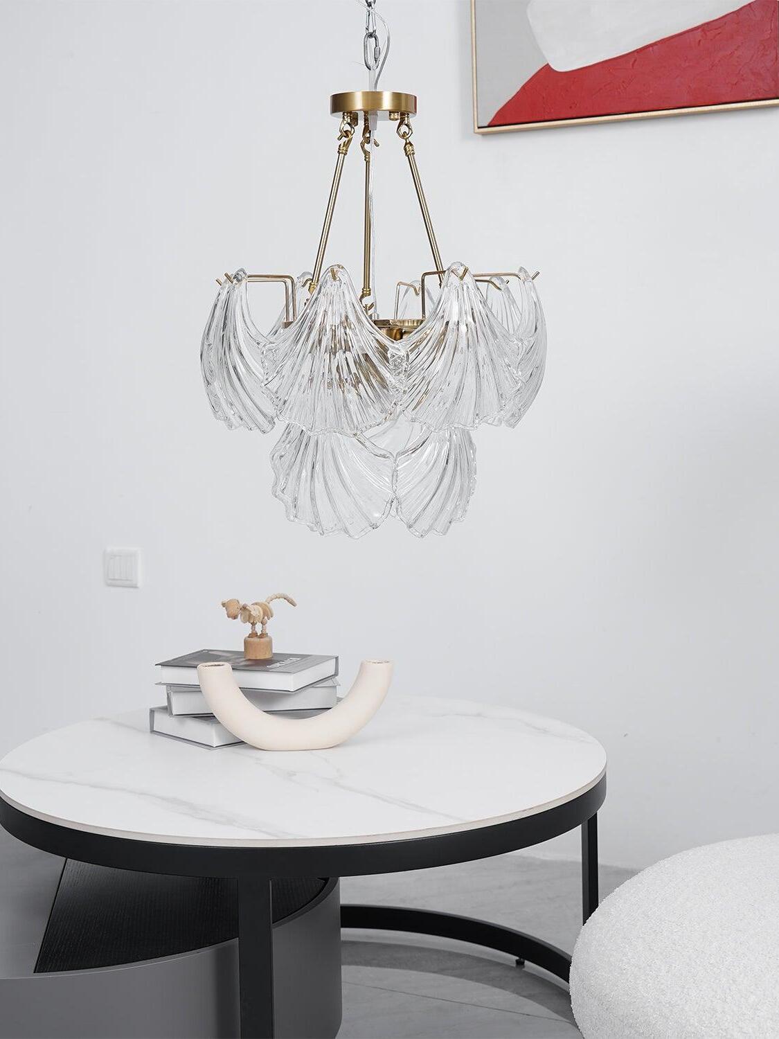 Shell-panel light with a visible chain above a white round table holding books and decorative objects