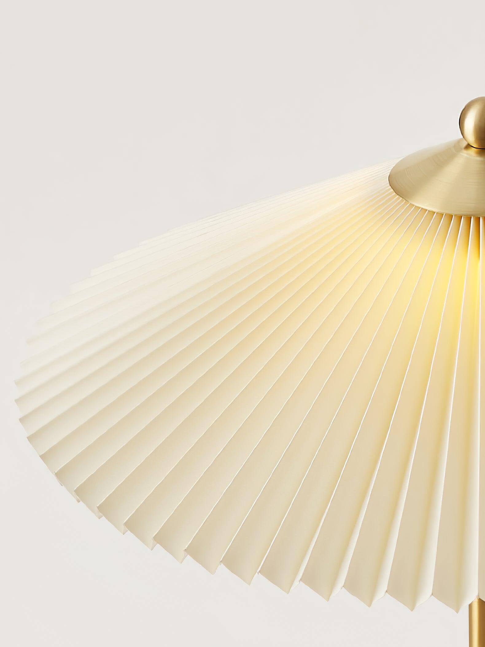 Angled detail of the pale shade pleats and gold-tone top cap near the finial