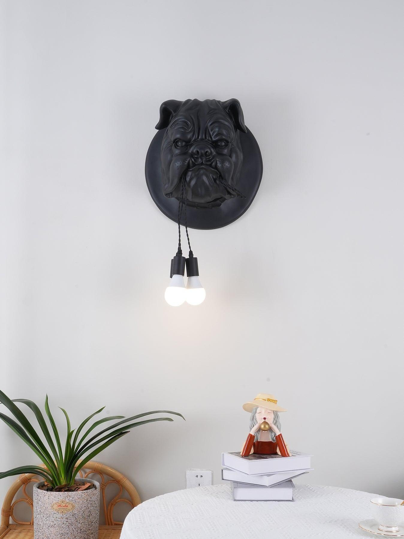 Black bulldog wall light above a table with a plant