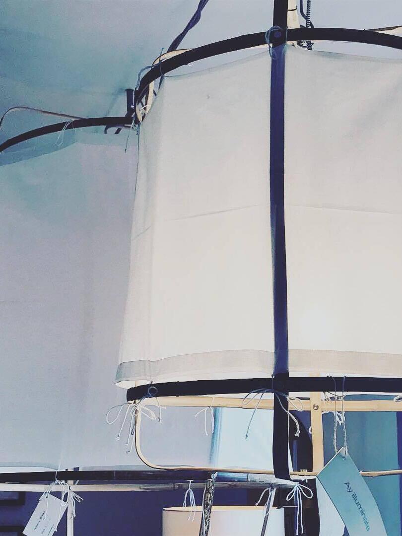 Close-up of white fabric sleeve hems and string ties on bent bamboo ribs, with neighbouring frames and hanging tag