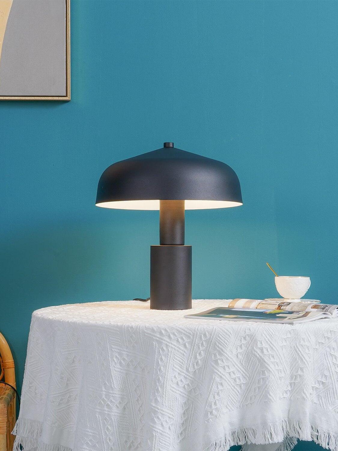 Black dome lamp level on table against blue wall