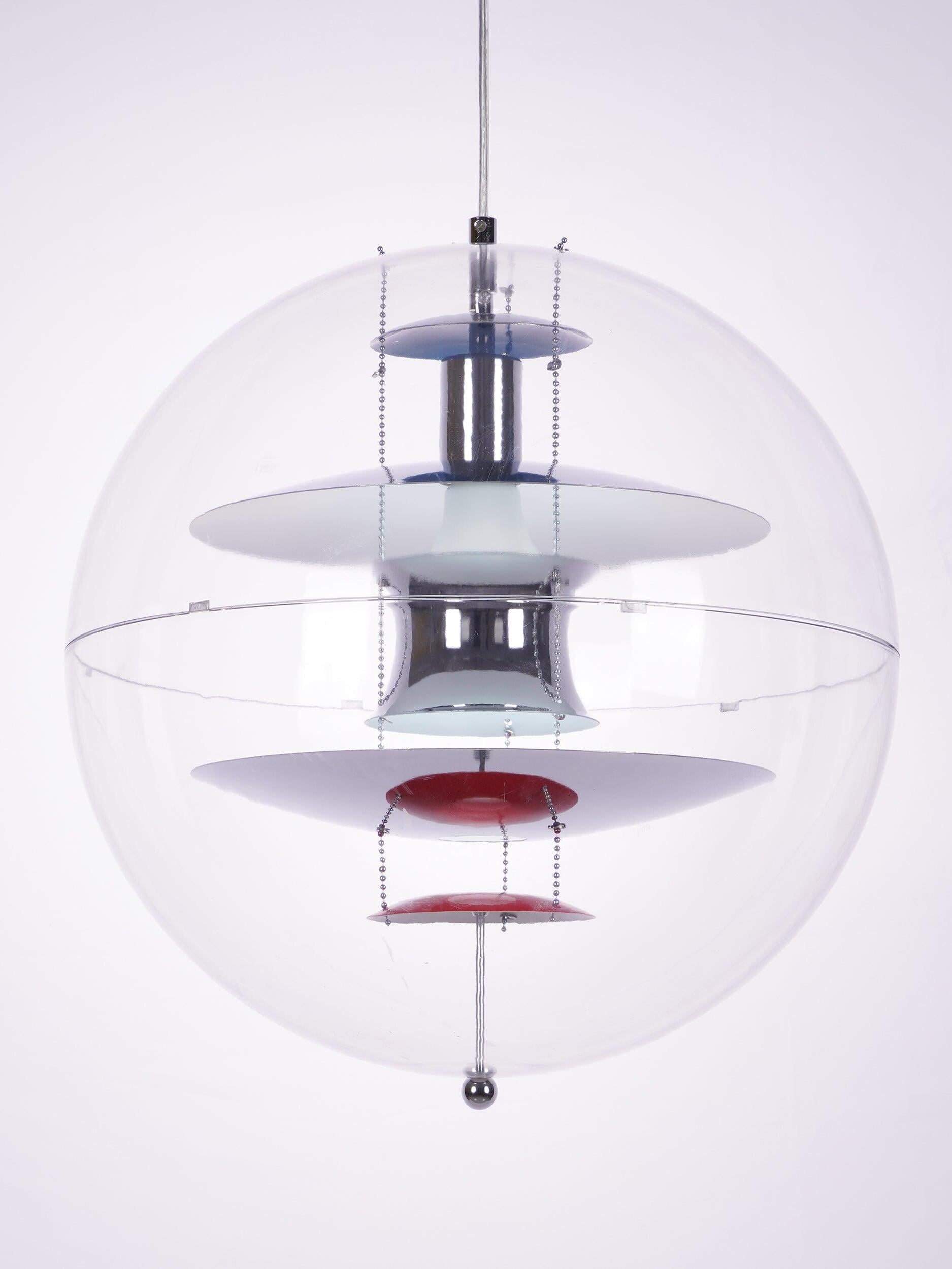 Close front view of the reflective hourglass-shaped centre, layered dishes and red lower disc inside the clear globe